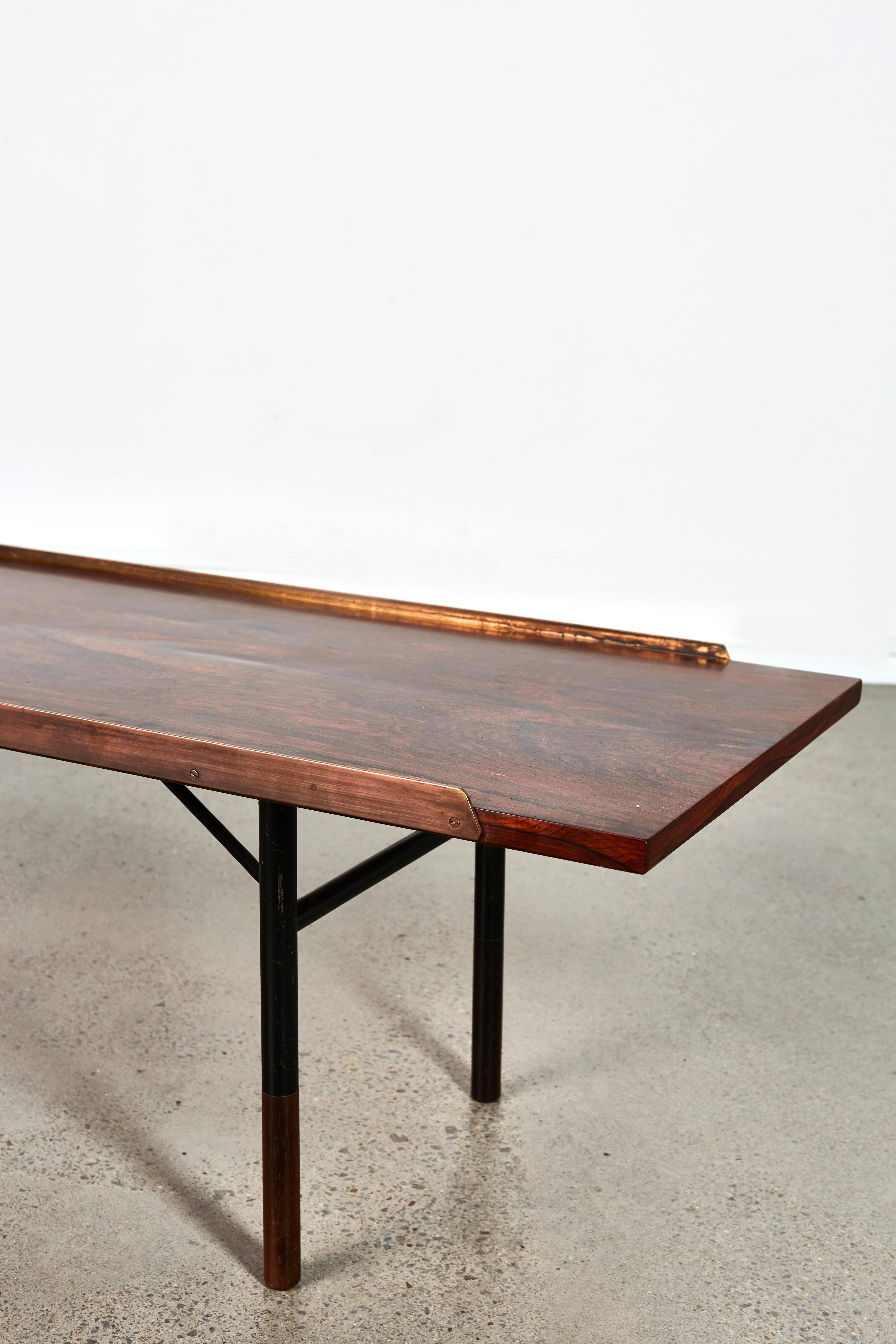 Beautiful bench designed by Finn Juhl for Bovirke in 1953 with anodized steel frame, rosewood and raised brass edges. Conceived by Juhl to be used as a bench and/or coffee table. 

This is the largest model and incredibly hard to find. An absolute
