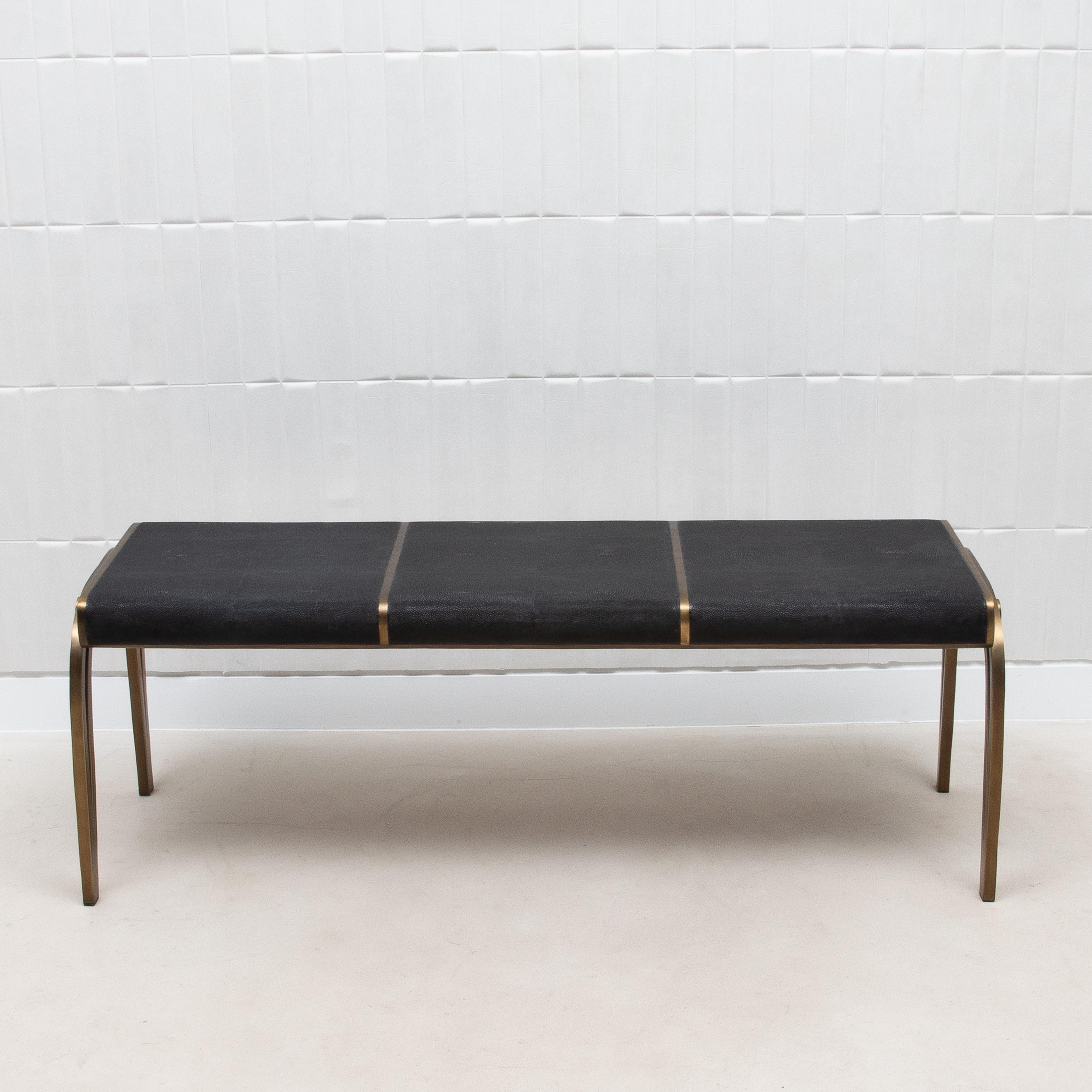 The Victoria bench by R&Y Augousti, crafted in luxurious black shagreen, is a true embodiment of elegance and sophistication. Its hand-crafted black shagreen top exudes a subtle texture that contrasts beautifully with the warm, rich tones of the