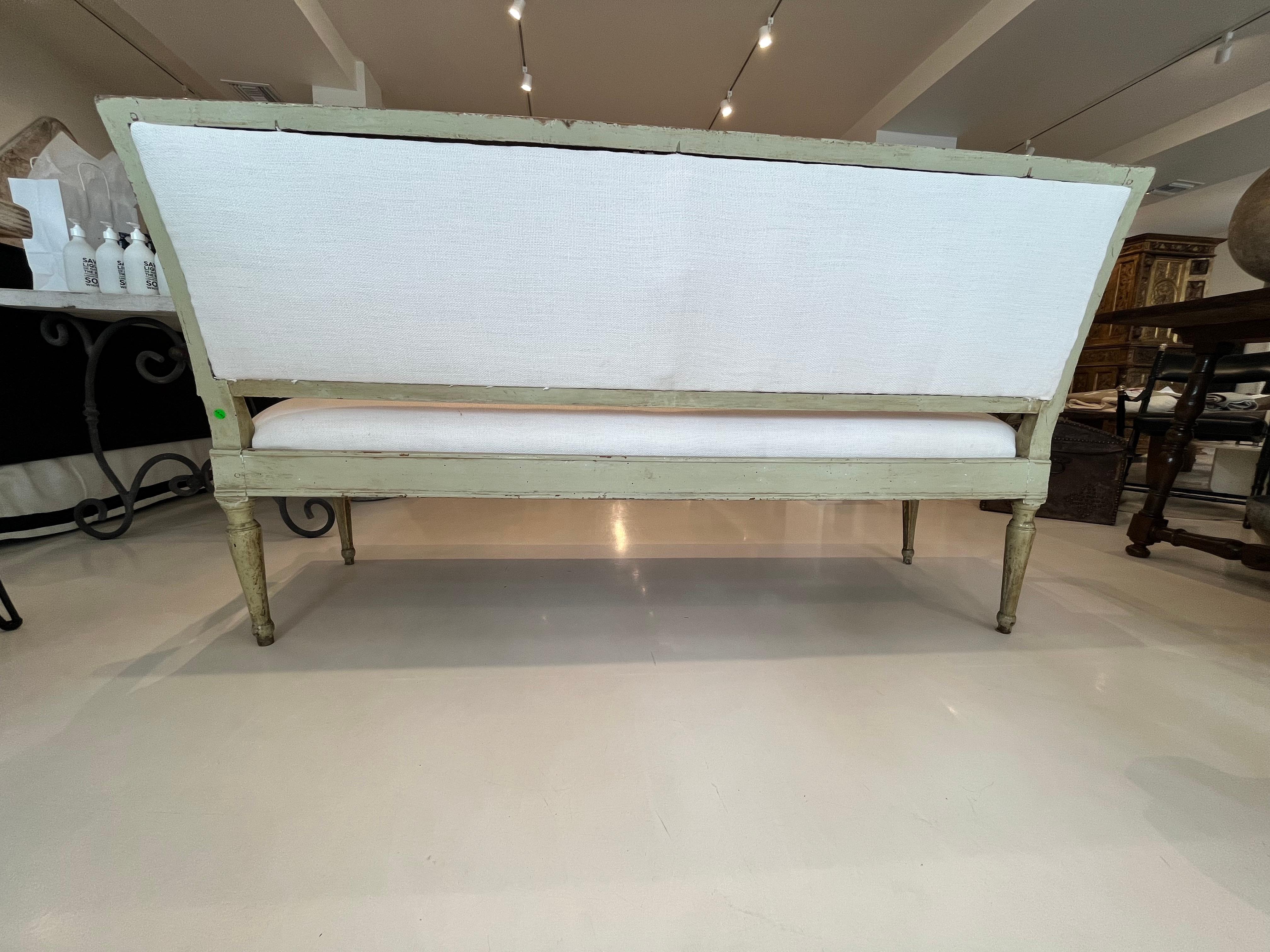 Bench with carved wood, gilding, and lacquer in pale green. Upholstery is White Belgian Linen.