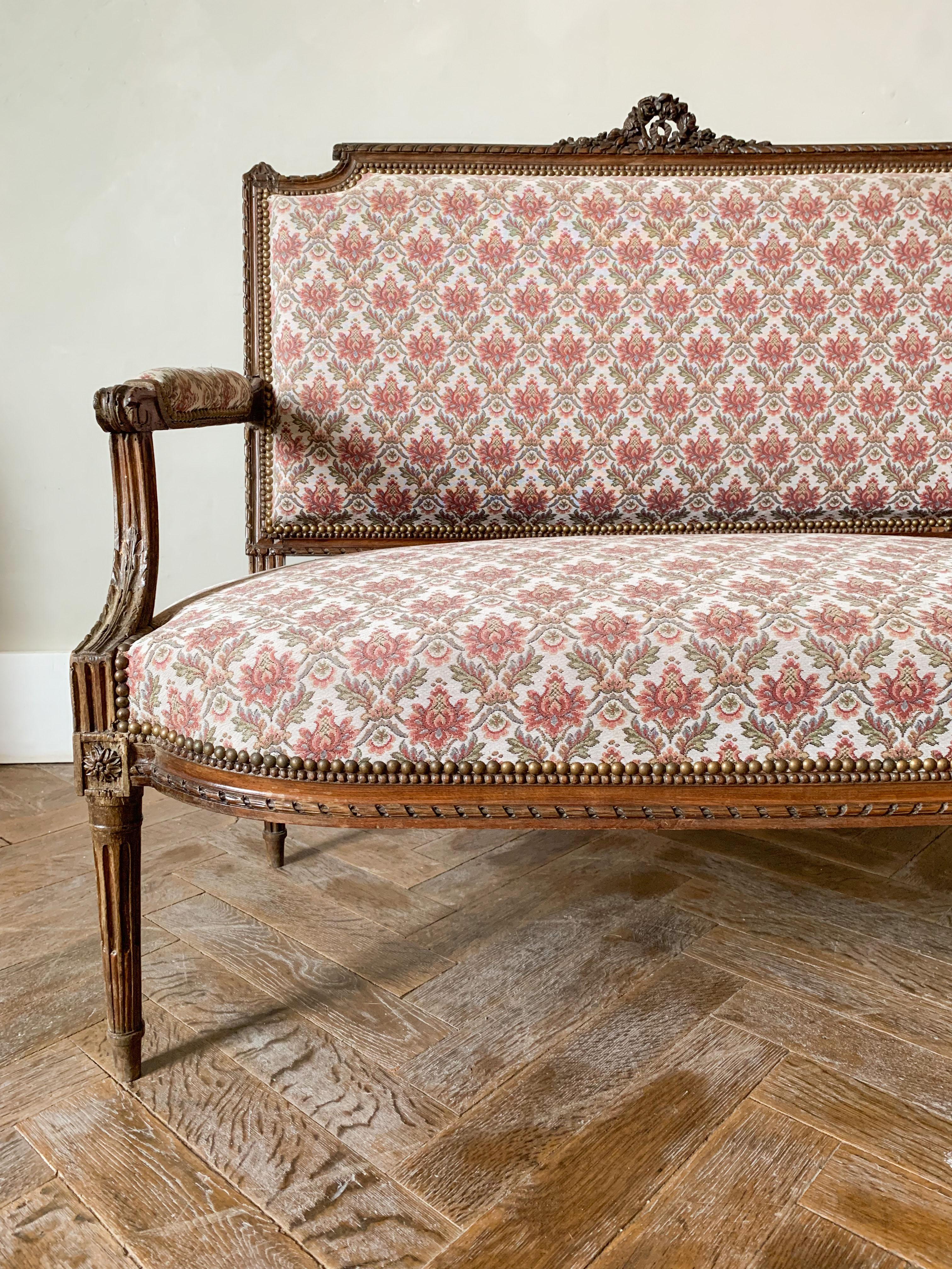 Beautiful two-seater bench from Louis XVI period resting on four fluted, tapered and rudentés. It is connected to the seat by fittings carved with flowers. The armrestes are decorated with acanthus leaves. The backrest is carved in its center with a