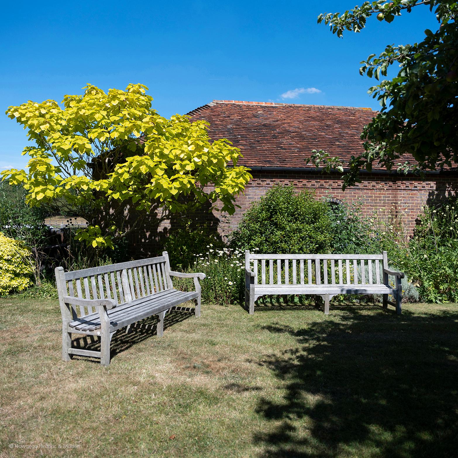 A massive, 8ft long, pair of stylish, classic, English country house, parkland, garden, patio or conservatory benches.  Made from the highest quality teak, probably Burmese, with a slat back and seat, the rail and slatted back above a concave seat