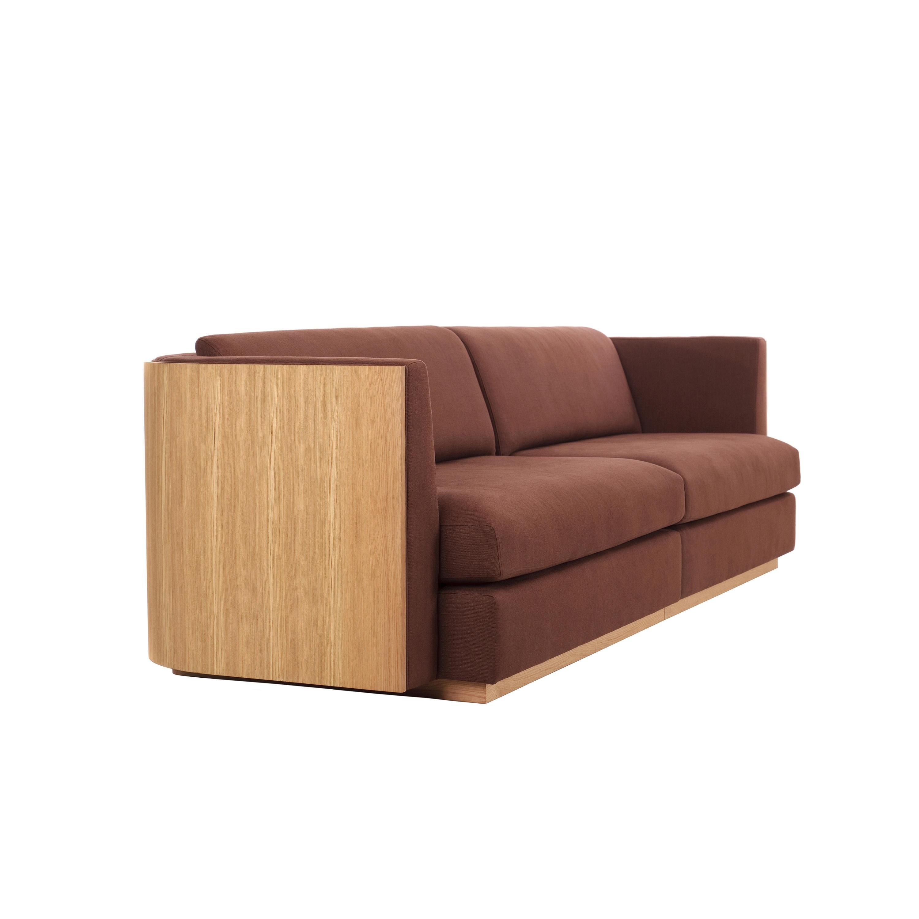 Dieses Sofa besticht durch seine markante Kombination geometrischer Formen. Er ist mit glattem Samtstoff gepolstert und bietet mit seinen gepolsterten Sitzen einen unvergleichlichen Komfort. Die freiliegende Holzrückwand ist ein raffiniertes Detail,