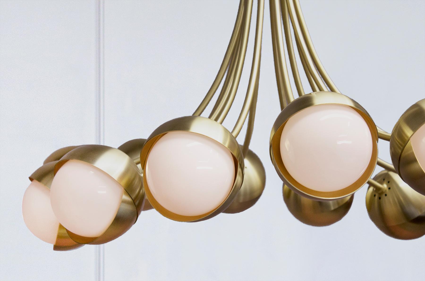 The Benedict™ 12-light chandelier puts the Benedict™ light assembly on full display. Laid out on a gently arching array, each nested pair of brass hemispheres cradles a white opal glass globe suspended by hand rolled brass stems. In addition to a
