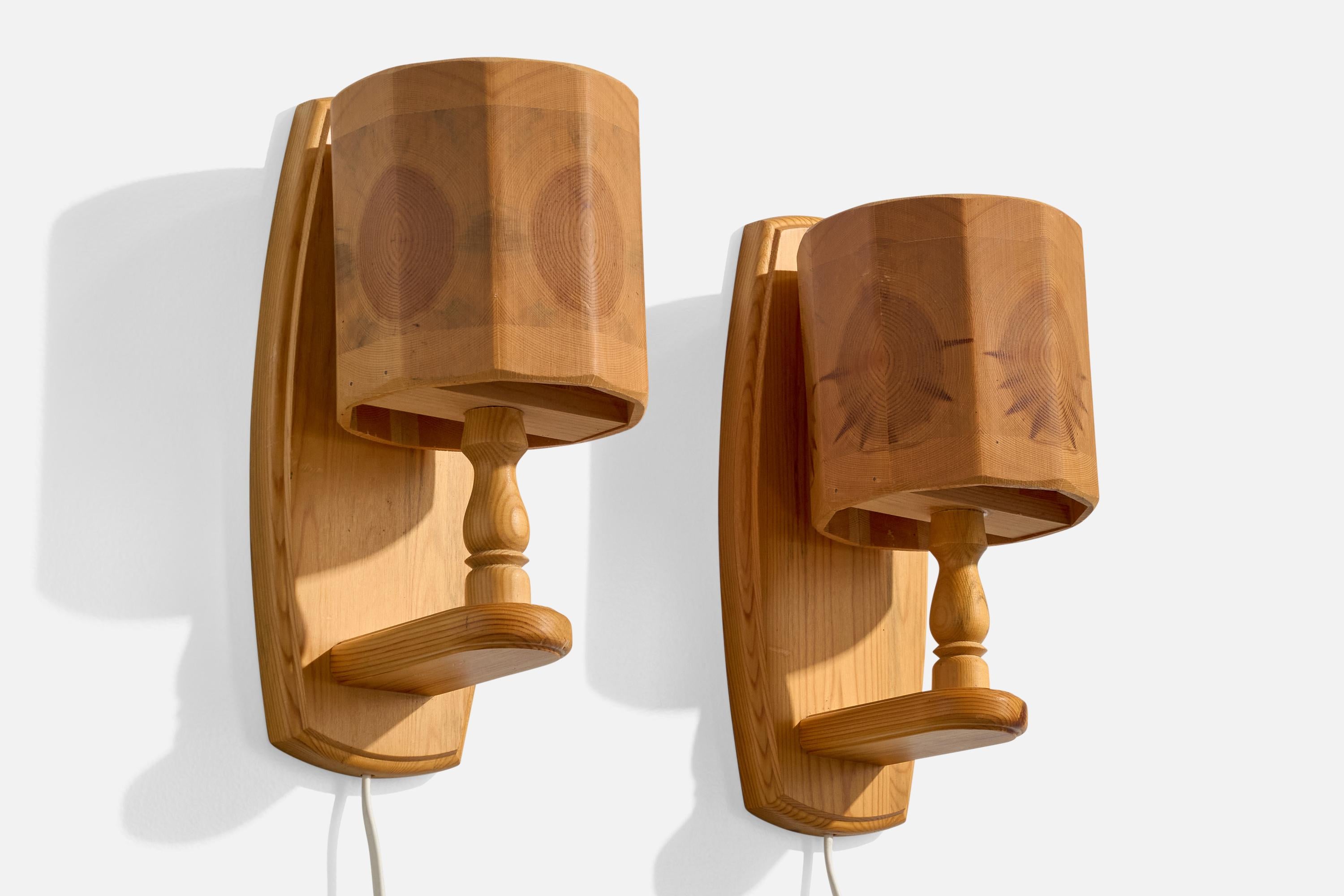 A pair of pine wall lights designed and produced by Bengt Slöjdare, Sweden, c. 1970s.

Overall Dimensions (Inches): 12” H x 5.3” W x 6.25“ D

Back Plate Dimensions (Inches): 12” H x 5” W x .8” D

Bulb Specifications: E-14

Number of Sockets (per