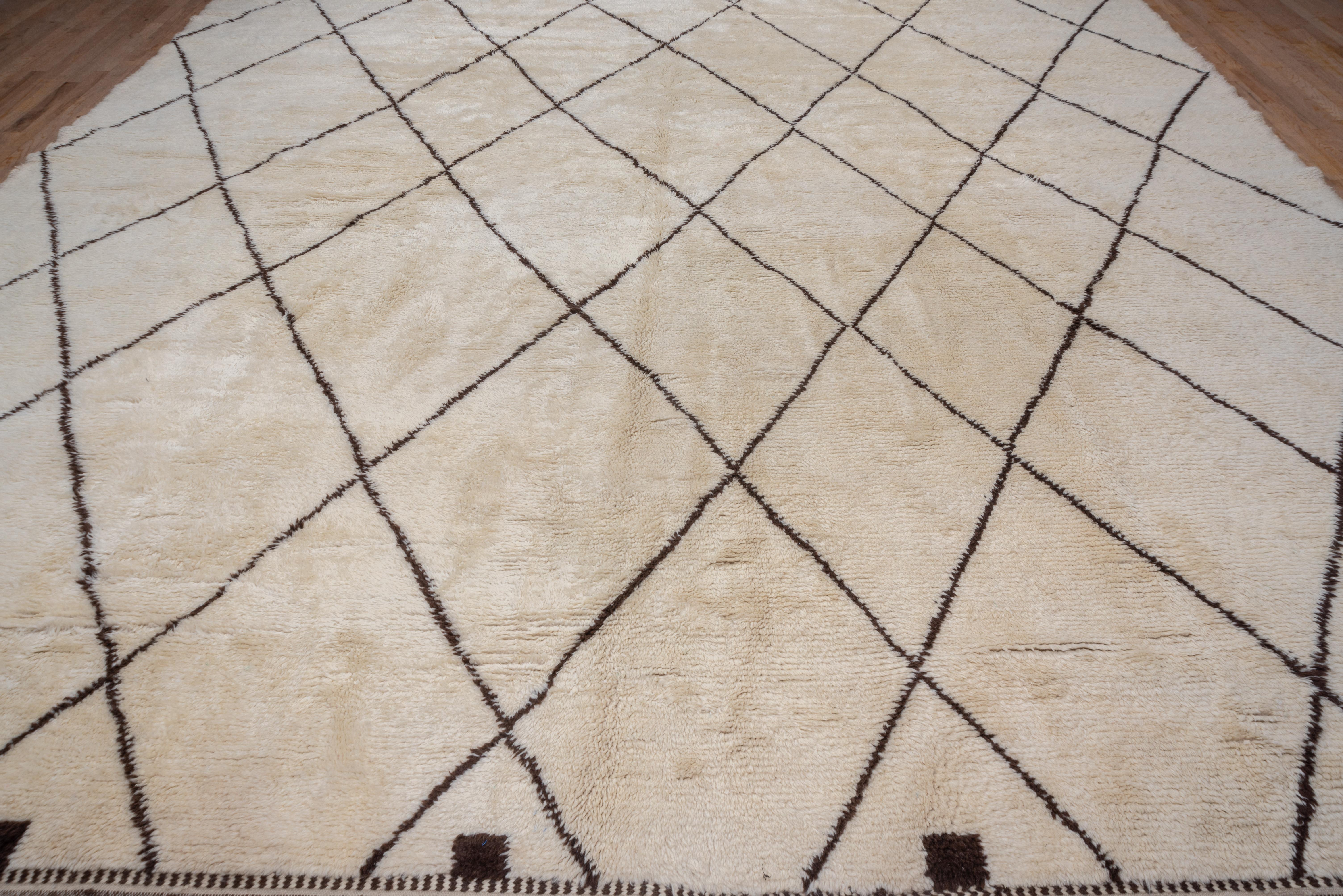 In the tribal Beni Ourain style, this high pile carpet features a slightly irregular tall lozenge, dark brown lattice on the sand ground. Small squares decorate the ends. Timeless and easy to place.