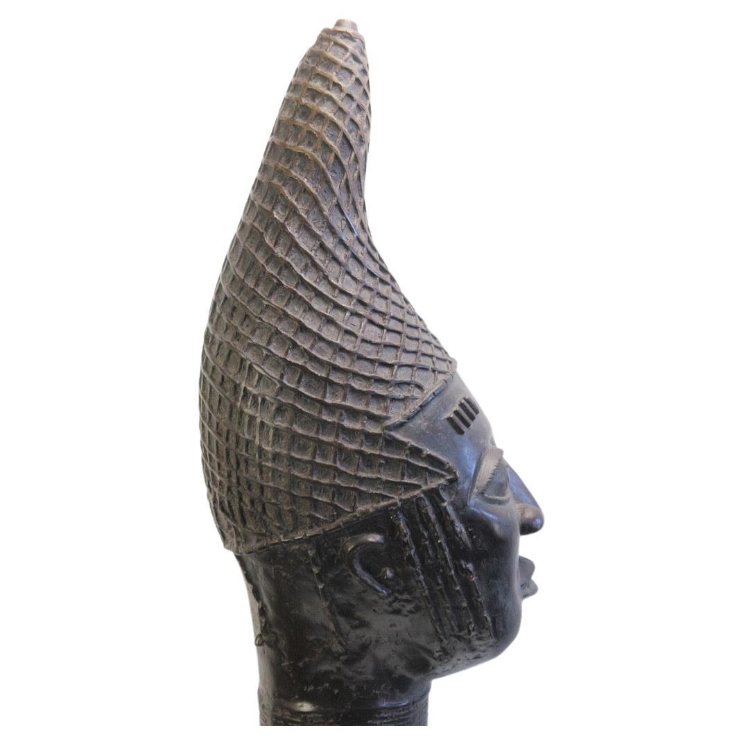 A beautiful unique bronze cast Edo Queens head. Bronze commemorative heads placed on altars are dedicated to past Iyobas (queen mothers). The most distinctive feature of this head is the marvelous high, forward-pointing headdress, which is a version