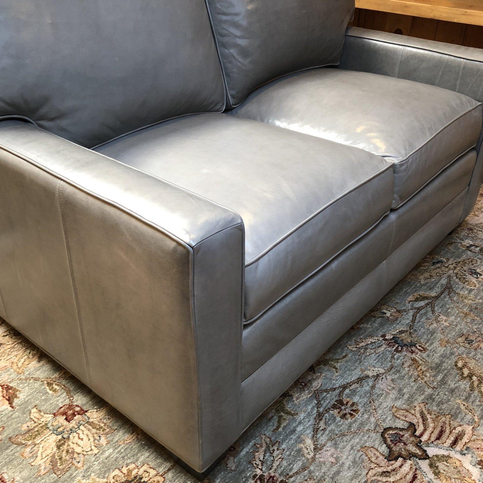 A Bennett Loveseat from Ethan Allen. Timeless, contemporary profile, the loveseat has simple track arms. The gray top grain leather envelopes loose welted back cushion with hook-and-loop fasteners, and foam seat cushions. An engineered hardwood