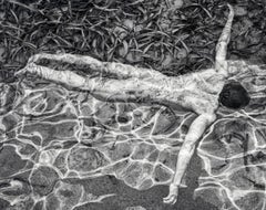 Natation (Un homme nu et sensuel se détend dans l'eau)  par un jour ensoleillé)