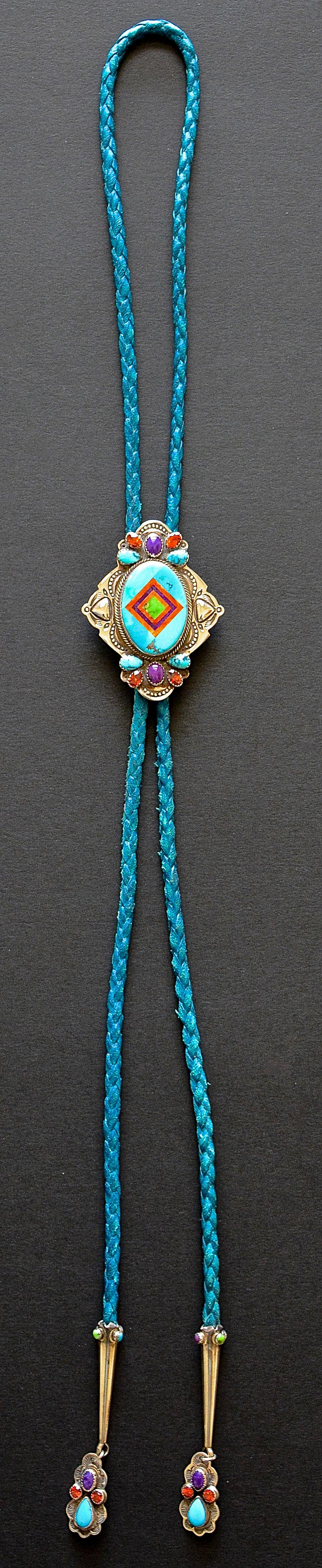 Unique Inlaid Multi-Gemstone and Sterling Silver Bolo Tie by Benny & Valerie Aldrich.

An exquisitely inlaid bolo made of many different stones including turquoise, spiny oyster, fire opal, sugilite, and varasite all set sterling silver. 

It has an
