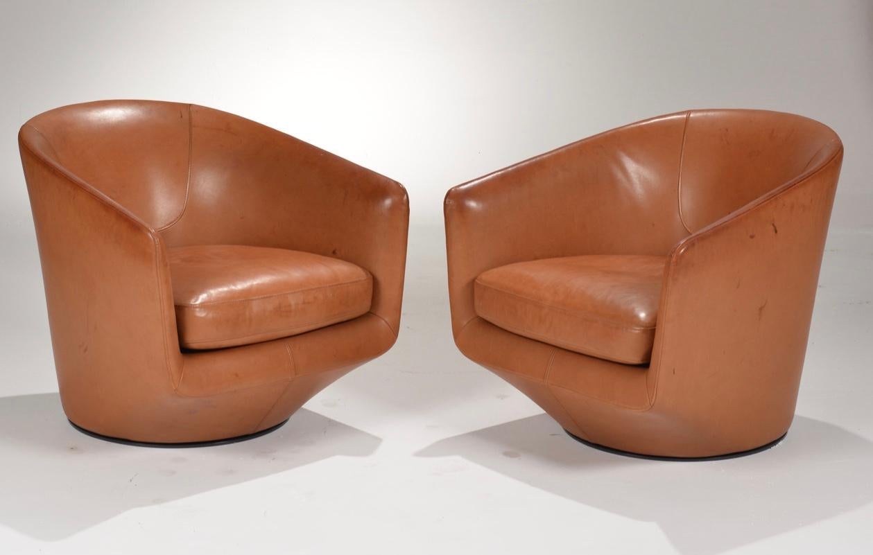 Pair of light brown leather swivel lounge chairs designed by Neils Bendsten. The chairs have a metal swivel base that rotates 360°. The leather is a beautiful tobacco color with some idyllic fading.