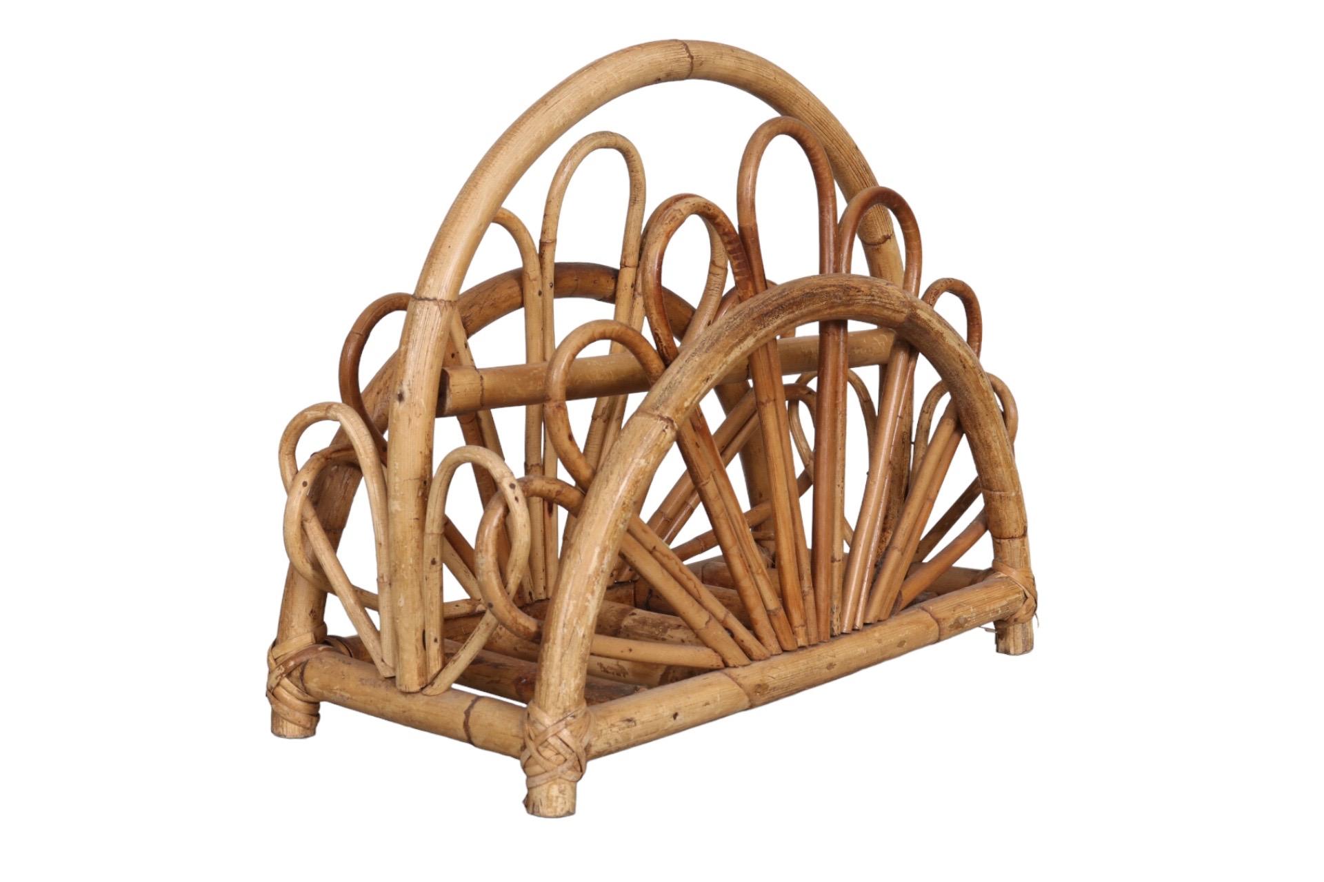 A midcentury magazine rack made of bent bamboo. Arched bamboo forms the frame and is secured at the base with wrapped rattan joints. Pencil wood bamboo is shaped into petals that form half daisys at each side.
