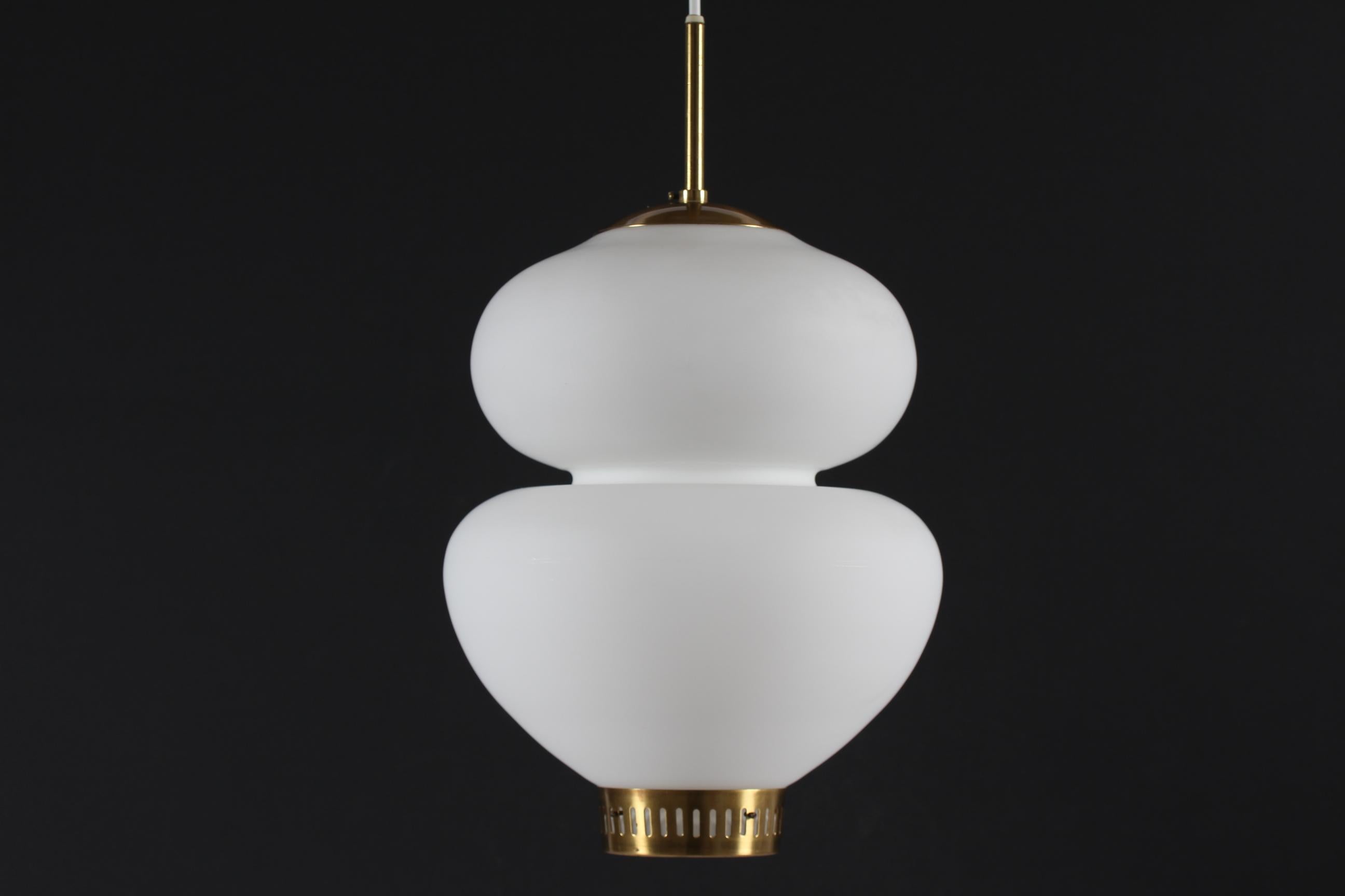 The Peanut pendent is made of white mouth-blown opaline glass with brass fittings. 
It was designed by Danish Bent Karlby (1912-1998) in 1946 and is manufactured by the Danish lamp company Lyfa. The pendant light has a beautiful organic