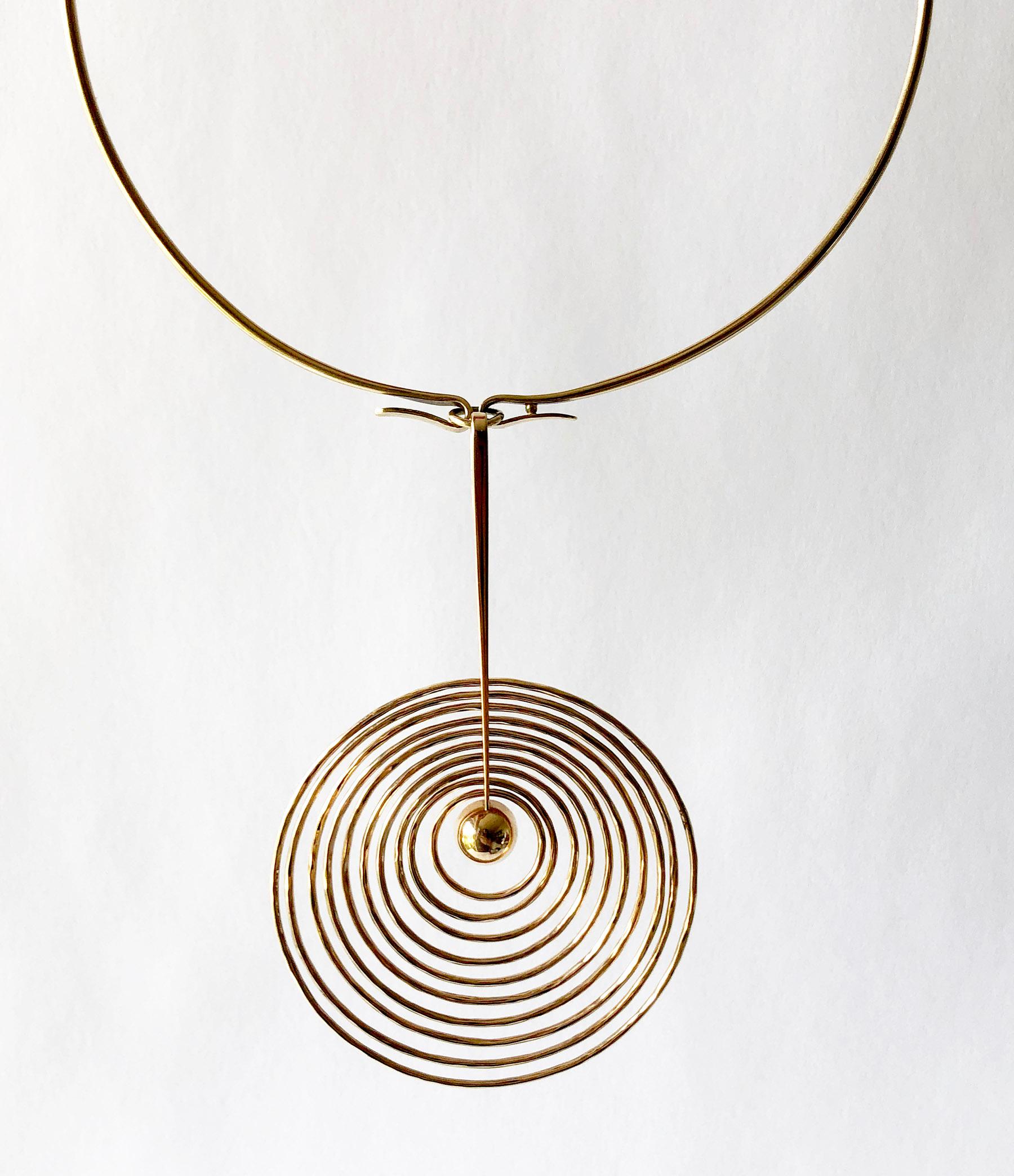 A 1960s 14k gold kinetic concentric circle pendant necklace and matching earrings created by Bent Gabrielsen of Denmark. The necklace torque measures about 15