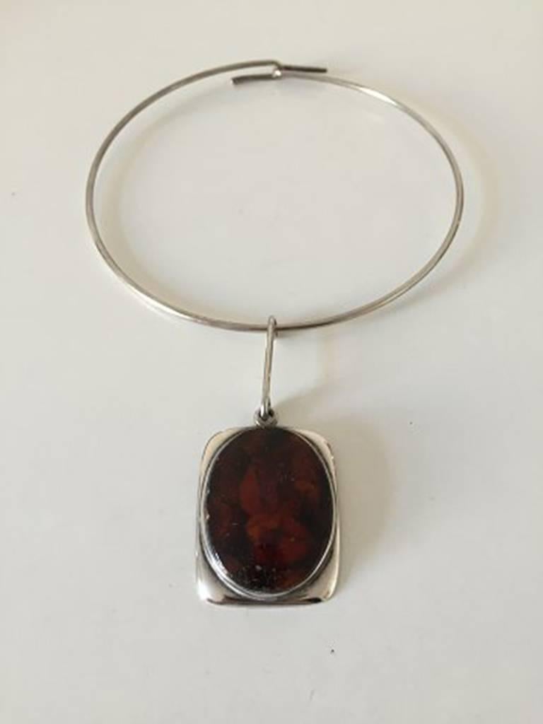 Bent Knudsen Necklace in sterling silver and amber. Marked Sterling, Denmark, Bent K, 35. Measures 12.5 cm / 4 59/64 inches in dia and the pendent 4.5 cm / 1 49/64 inches. In really good shape. The amber piece does have some wear. 