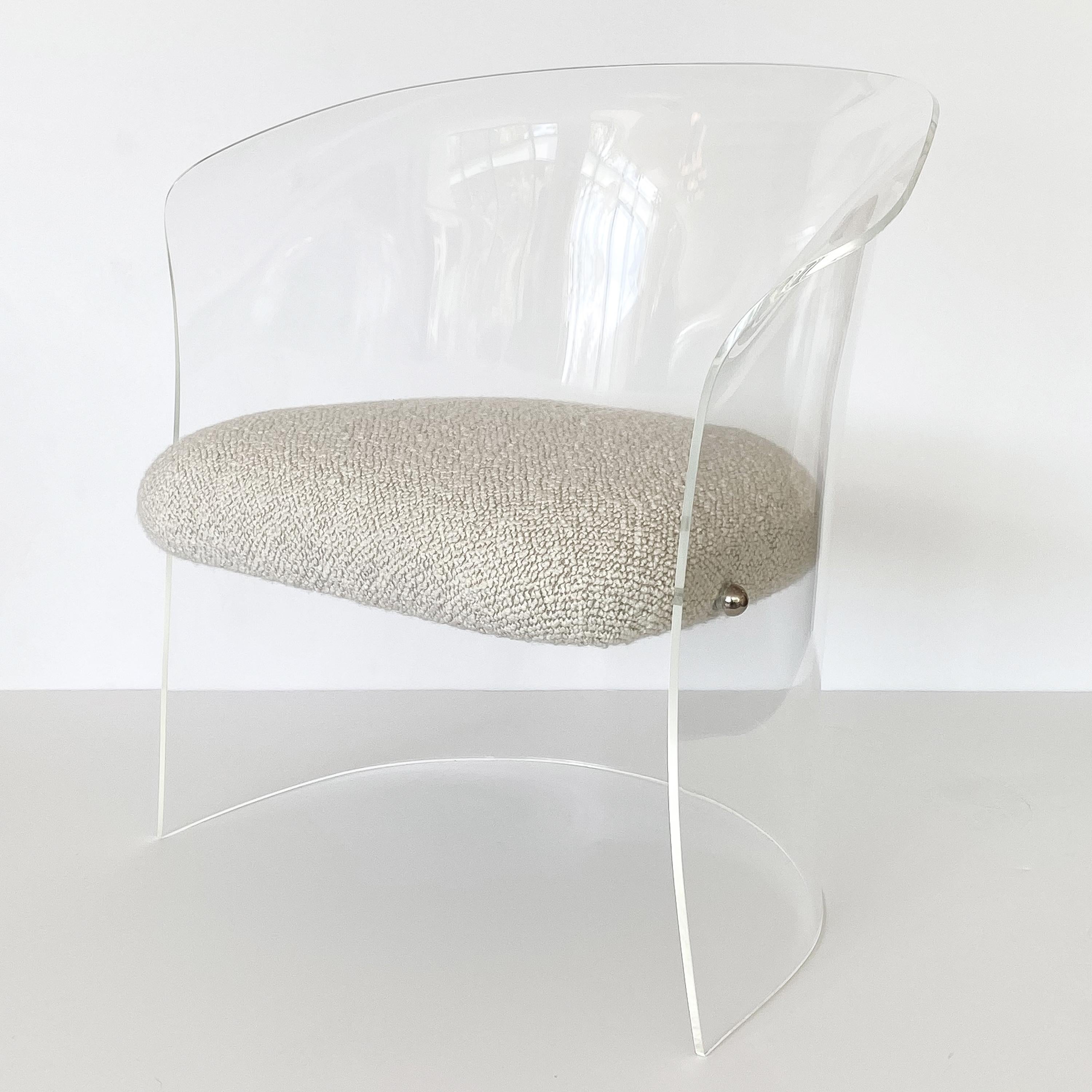 A Lucite barrel back occasional chair, circa 1970s. This chair is comprised of a single sheet of bent and molded Lucite. A single seat is suspended within the form by chrome dome shaped connectors. Newly upholstered in a chunky textured pale stone