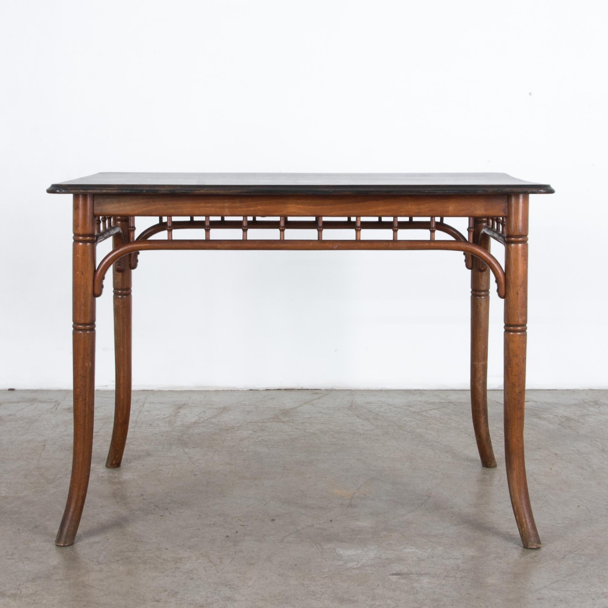From Austria circa 1900, this wooden table is attributed to Thonet, a pioneering maker of high volume furniture production in Central Europe. Bent wooden legs and supports give an elegant curve in this piece, complimented by subtle carved