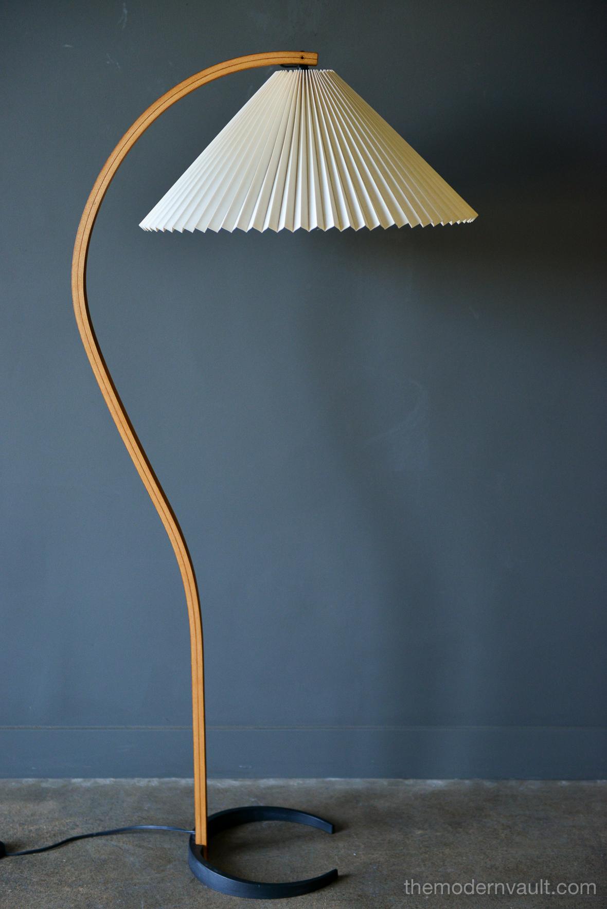 Mads Caprani floor lamp, circa 1971 by Danish manufacturer Mads Caprani AS. This vintage lamp features sculptural bent plywood stand with en elegant curve, a cast iron crescent shaped base, and new pleated linen shade. Original floor switch and