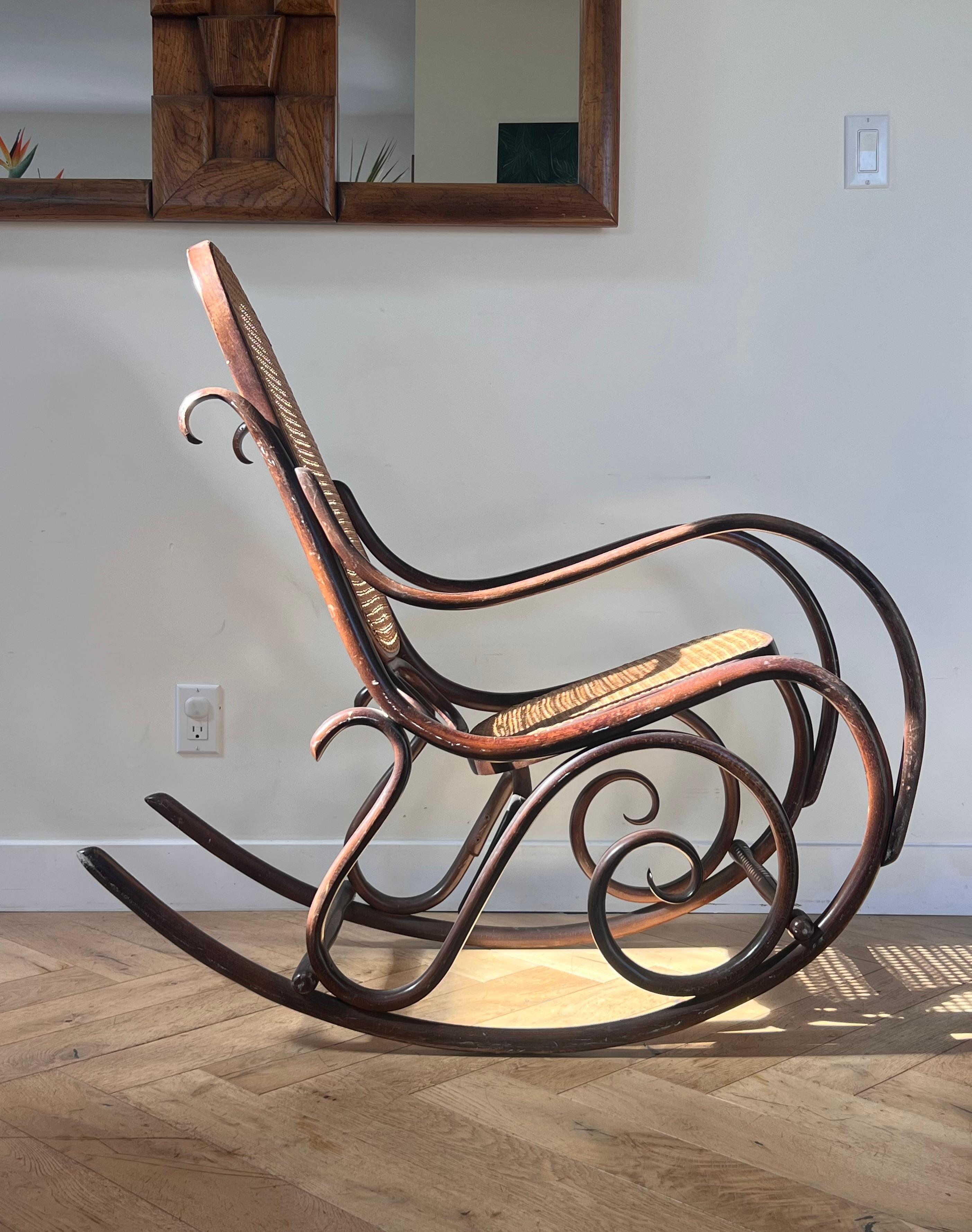 A bentwood rocker attributed to Thonet, late 19th or early 20th century. Featuring art nouveau whiplash curves and real wicker caning. Made in Poland (possibly at the Radomsk Thonet factory (see R1 / Made in Poland stamp). Significant wear to wood