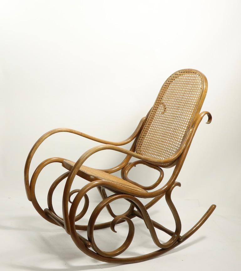 Stylish and comfortable bentwood rocking chair by Thonet having caned backrest and seat. This example is in clean original condition, fully and correctly marked. Total H 40.5 x Arm H 25 x Seat H 19 inches.