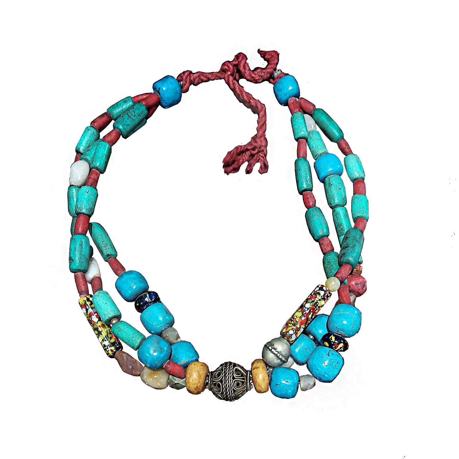 A long Berber necklace, hand-crafted with stone beads and wool, with a round filigree silver accent. Morocco, early 20th Century. 

Green and blue amazonite, red coral, glass and stone beads and semi-precious stones are combined in this beautiful