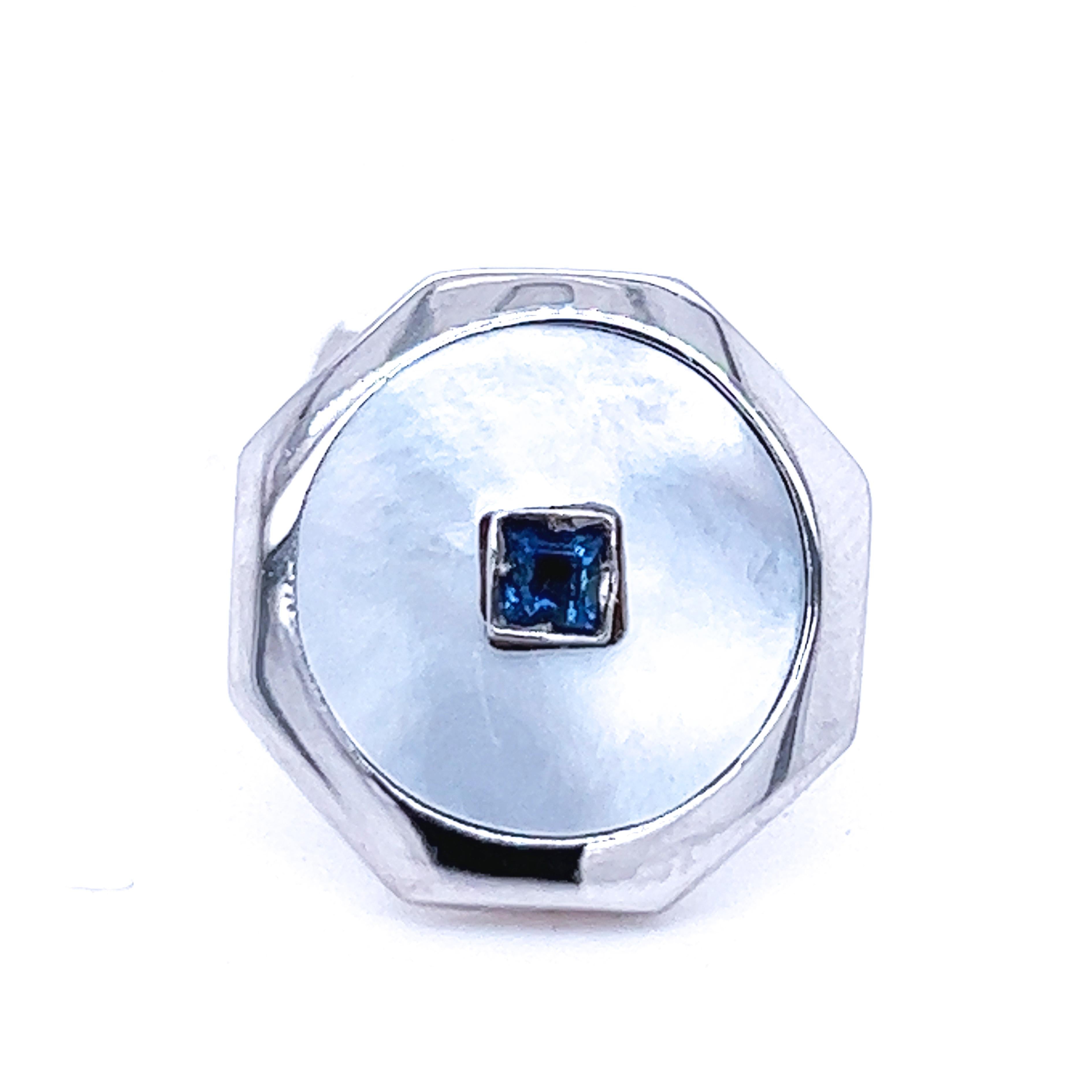 Saphir bleu royal naturel de 0,25 carat de forme carrée, absolument chic et intemporel, dans un disque de nacre émaillé à la main, serti dans une monture octogonale en or blanc,  t-bar arrière.
Dans notre élégant coffret et notre pochette en cuir