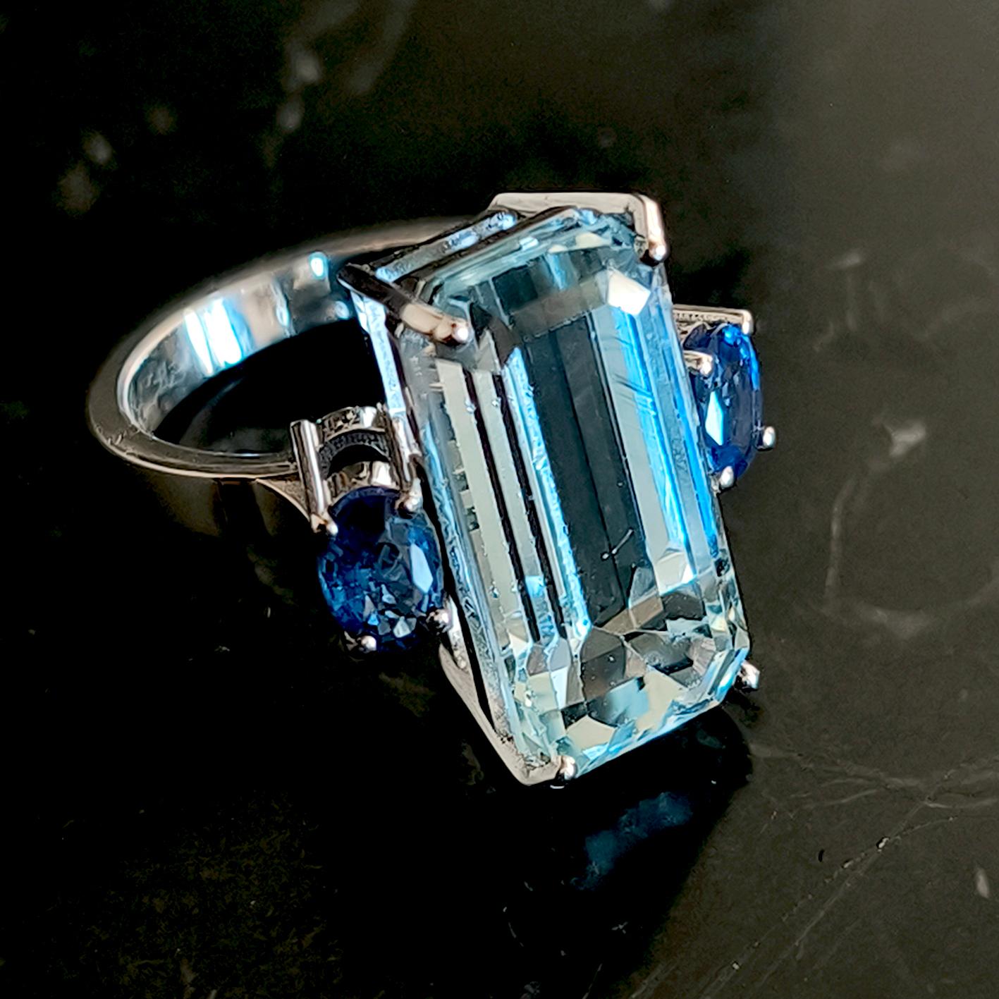 Einzigartiger 10,24 Karat natürlicher brasilianischer Aquamarin im Smaragdschliff (0,74 in der Länge 0,37 in der Breite, 18,88x9,52 mm) in einer schicken und doch zeitlosen Cocktail-Fassung mit zwei 1,13 Karat natürlichem blauen Ceylon-Saphir in 18