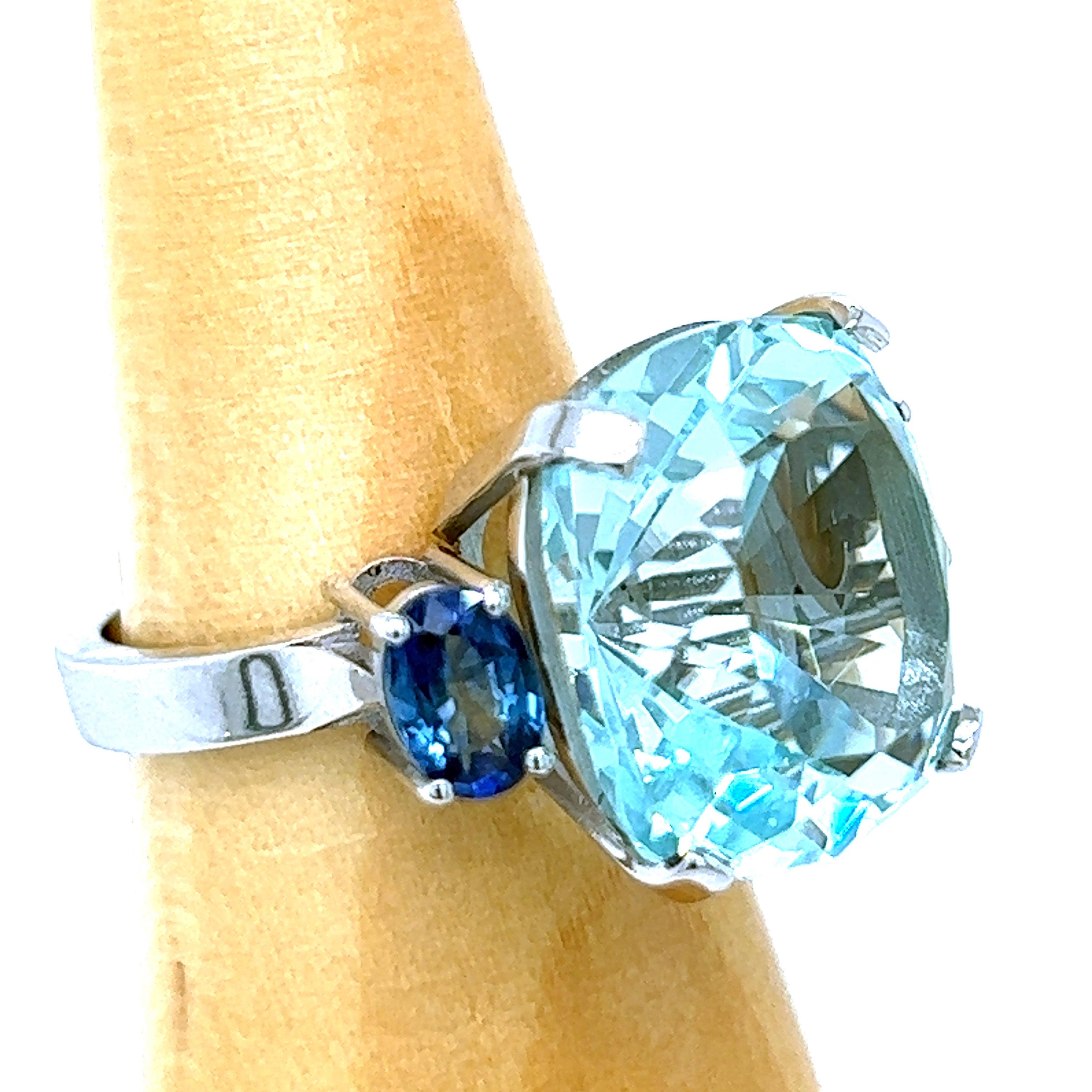 One-of-a-kind 12 Carat Antik Cushion Cut Natural Brazilian Aquamarine(0.602in lenght 0.534in width, 15,26x13,54mm) in a Chic yet Timeless two 1.09 Carat Natural Ceylon Oval Blue Sapphire 18Kt White Gold Cocktail Setting.
We are proud to offer this