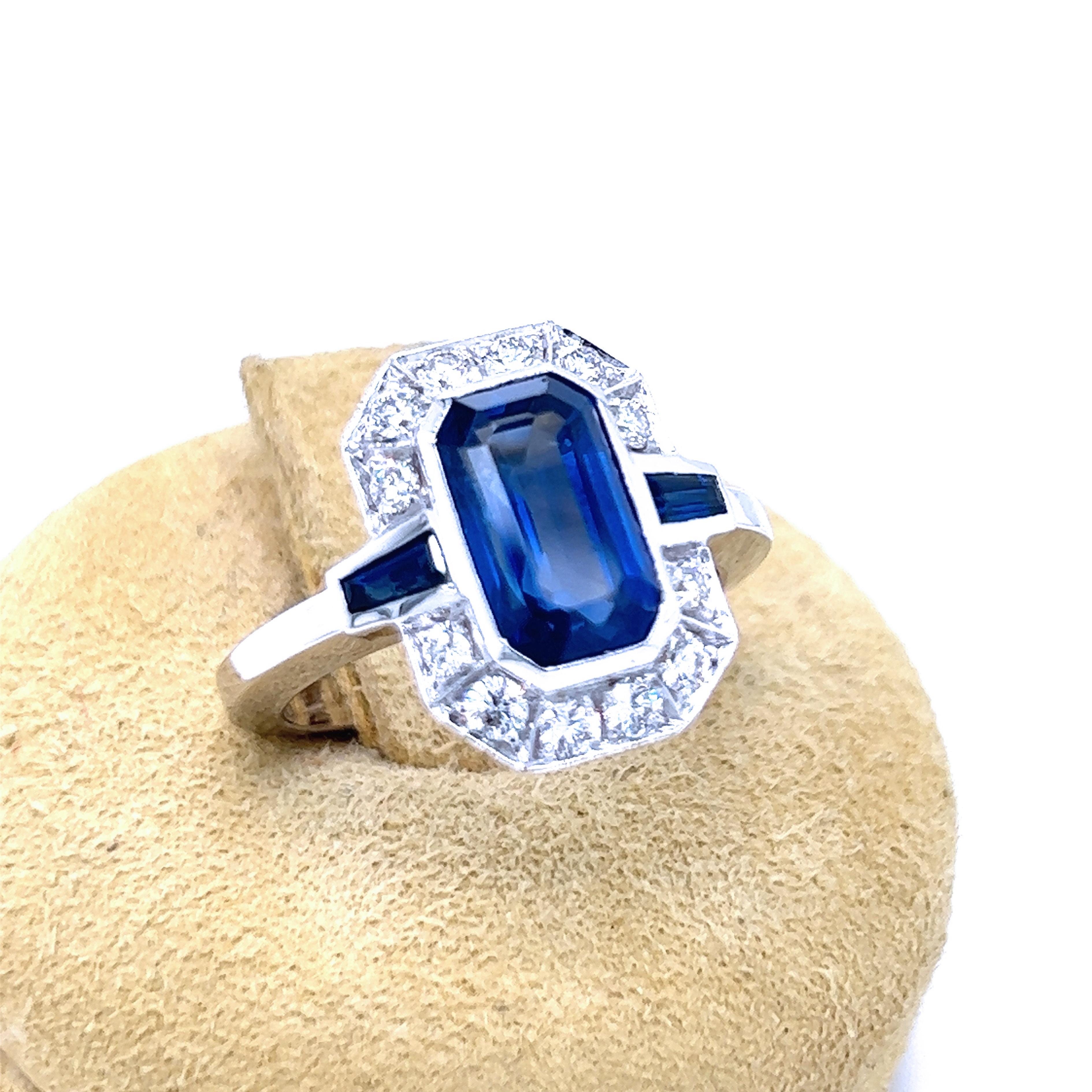 Awesome, IGI Certified, 3.17Kt (10.26x6.10x4.5mm) Royal Blue Sapphire Emerald Cut in a Top Quality 0.43Kt White Diamond Brilliant Cut, 0.26Kt Sapphire Tapered Baguette Timeless White Gold Setting Ring.
As stated in IGI Certicate 522236955 May 3