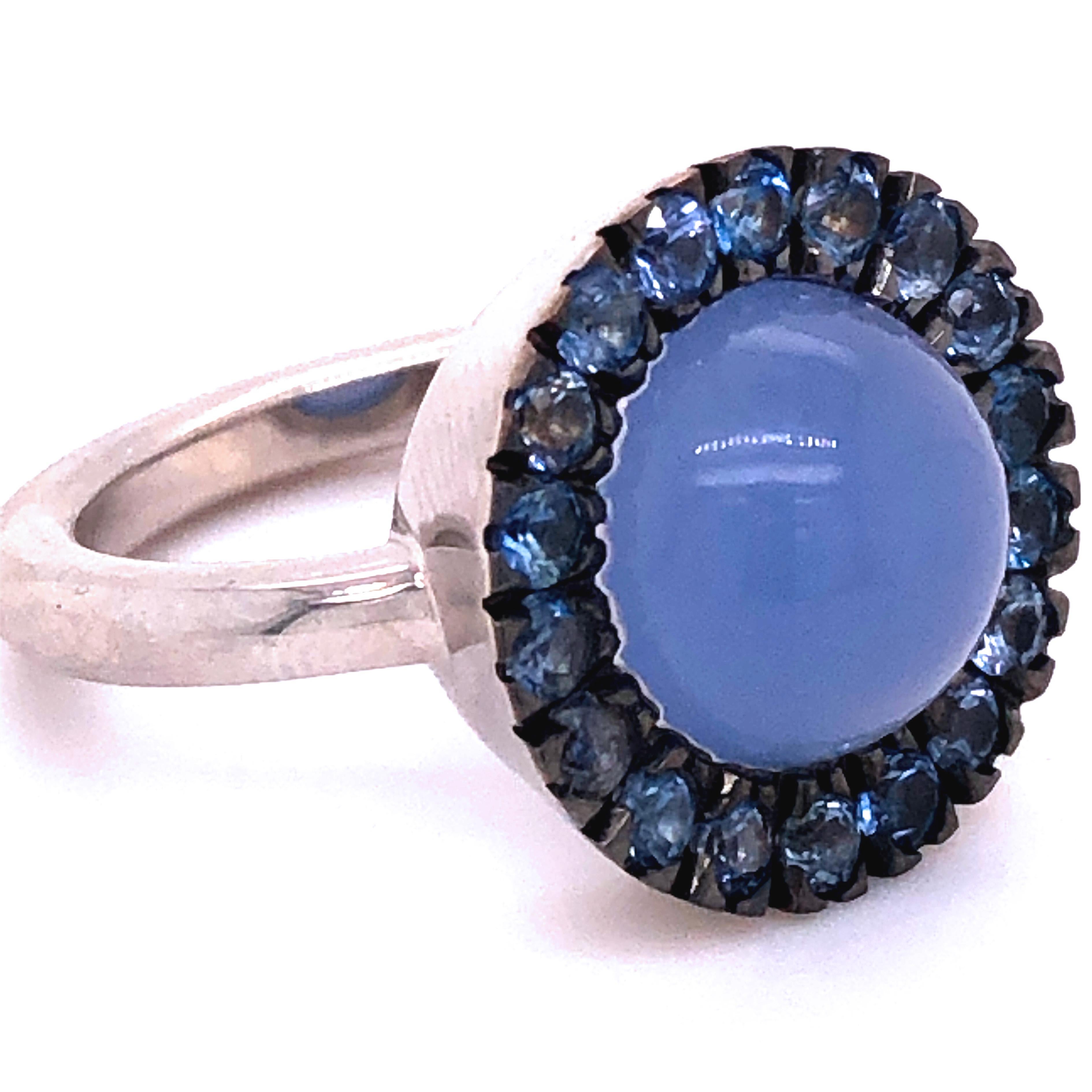 Chic, Unique yet Timeless Contemporary Cocktail Ring featuring a Natural 6.5Kt Blue Chalcedony Round Cabochon surrounded by 1.45Kt Natural Vivid Blue Sapphire in an elegant White Gold contemporary Halo Setting: a Magical, Mesmerizing Piece.
In our
