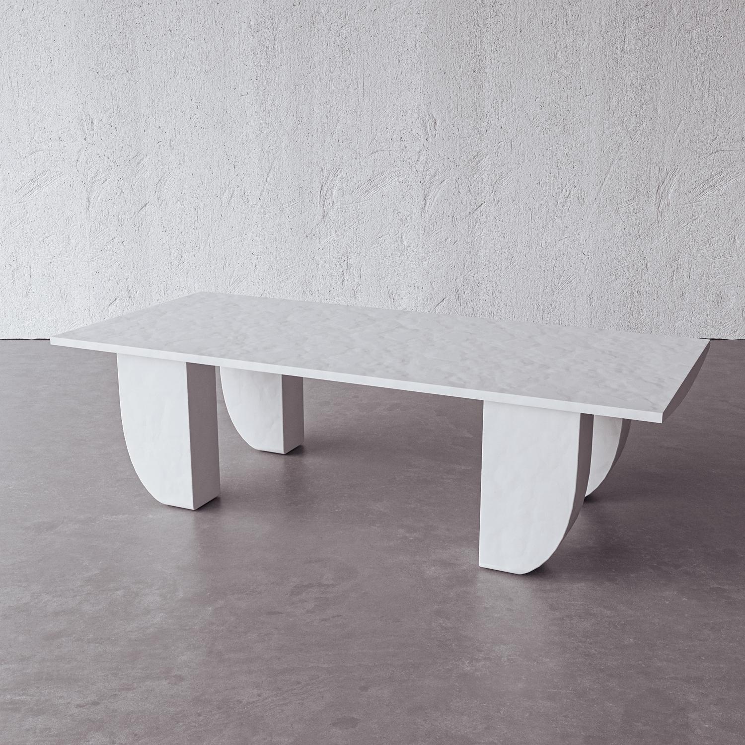 Sculpted in plaster, arced legs support a hand-cast rectangular top in this geometric, modern cocktail table. Handmade by artisans in Vietnam, the simple white surface complements a decorative interior and provides a blank space for collectible