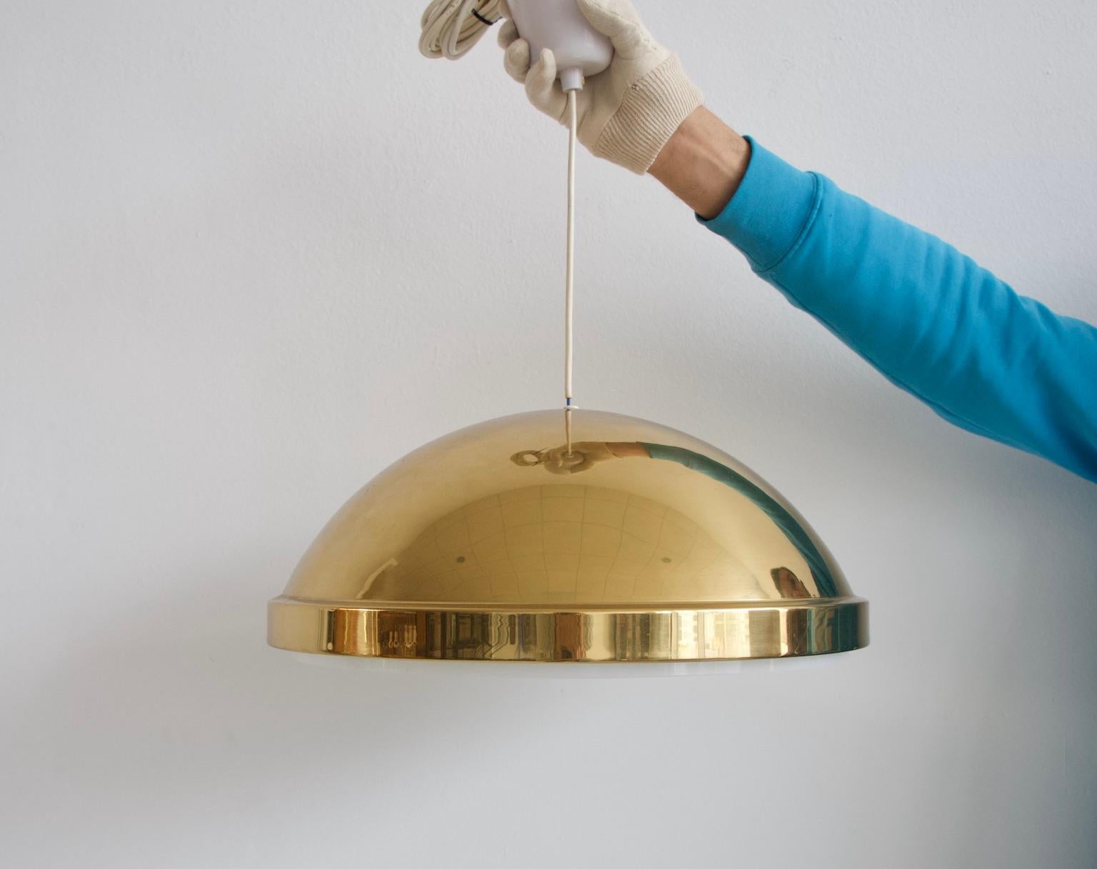 Lampada a sospensione svedese prodotta da Bergboms negli anni '60 circa. Paralume rotondo in ottone con schermo in acrilico bianco. Leggera usura dovuta all'età.