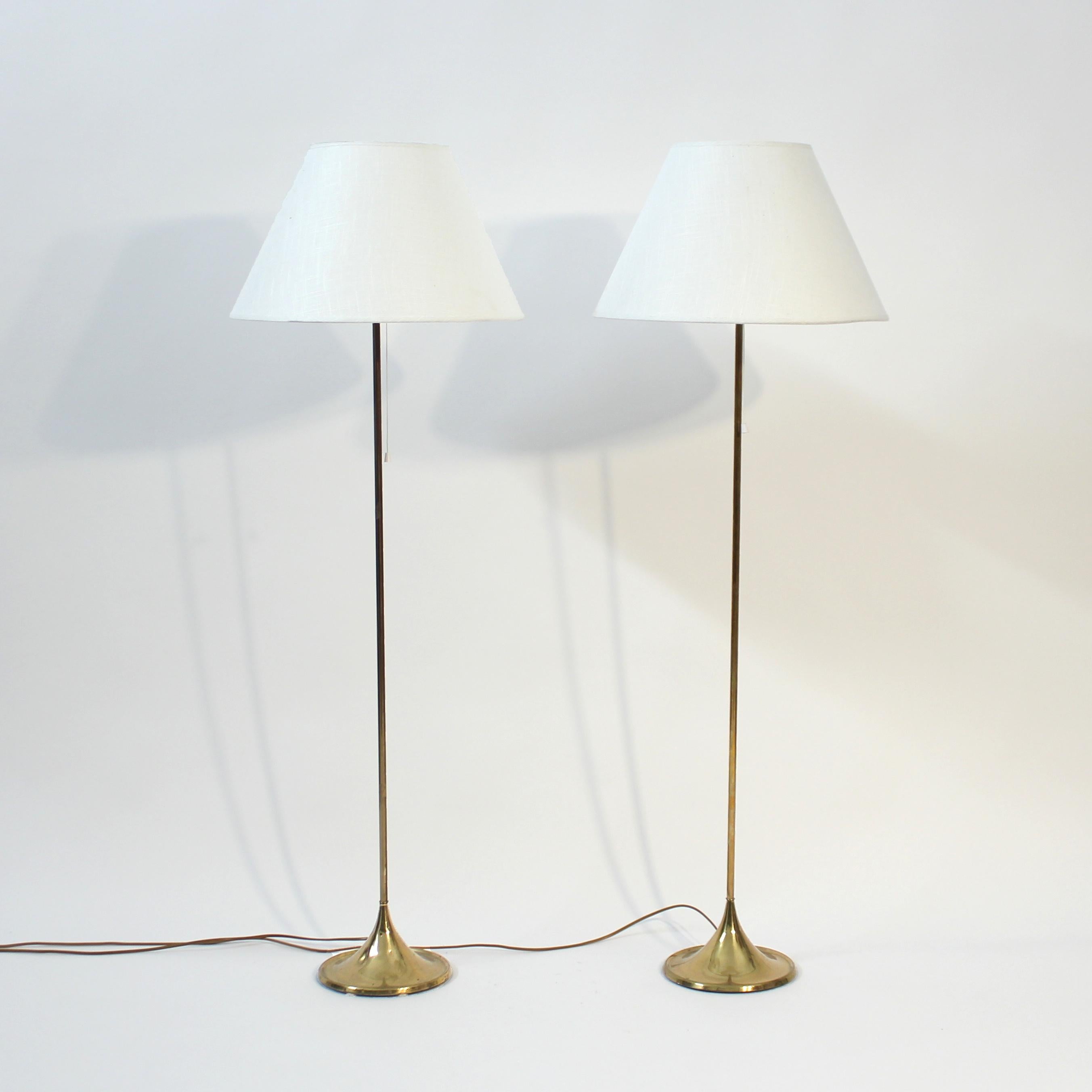 ir of 1960s Bergboms floor lamp, model G-25. Brass stem on top of a round, almost cone shaped brass base. Mounted with later off-white fabric shades. Light ware consistent with age and use.