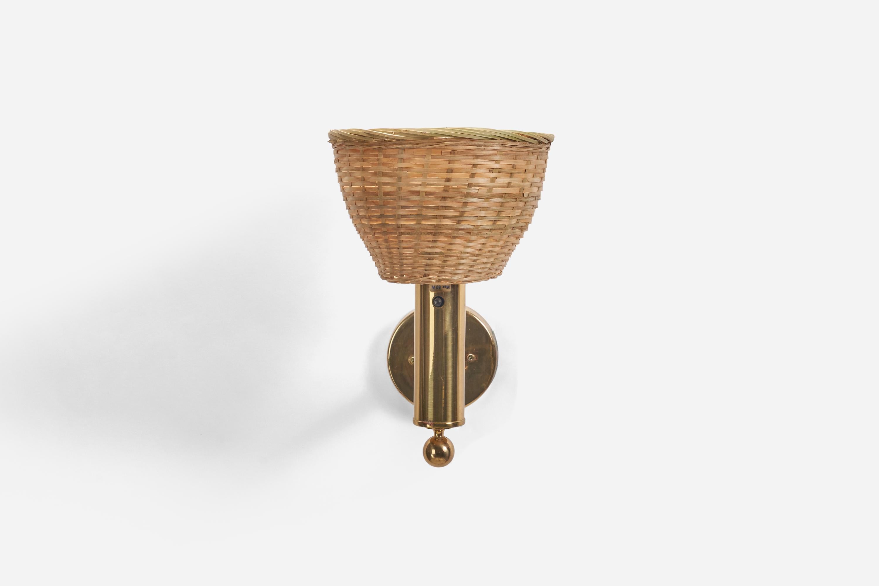 A brass and rattan sconce designed and produced by Bergboms, Sweden, 1970s.

Sold with lampshade. Dimensions stated are of sconce with lampshade.

Dimensions of back plate (inches) : 3.86 x 3.86 x 0.82 (height x width x depth)

Socket takes