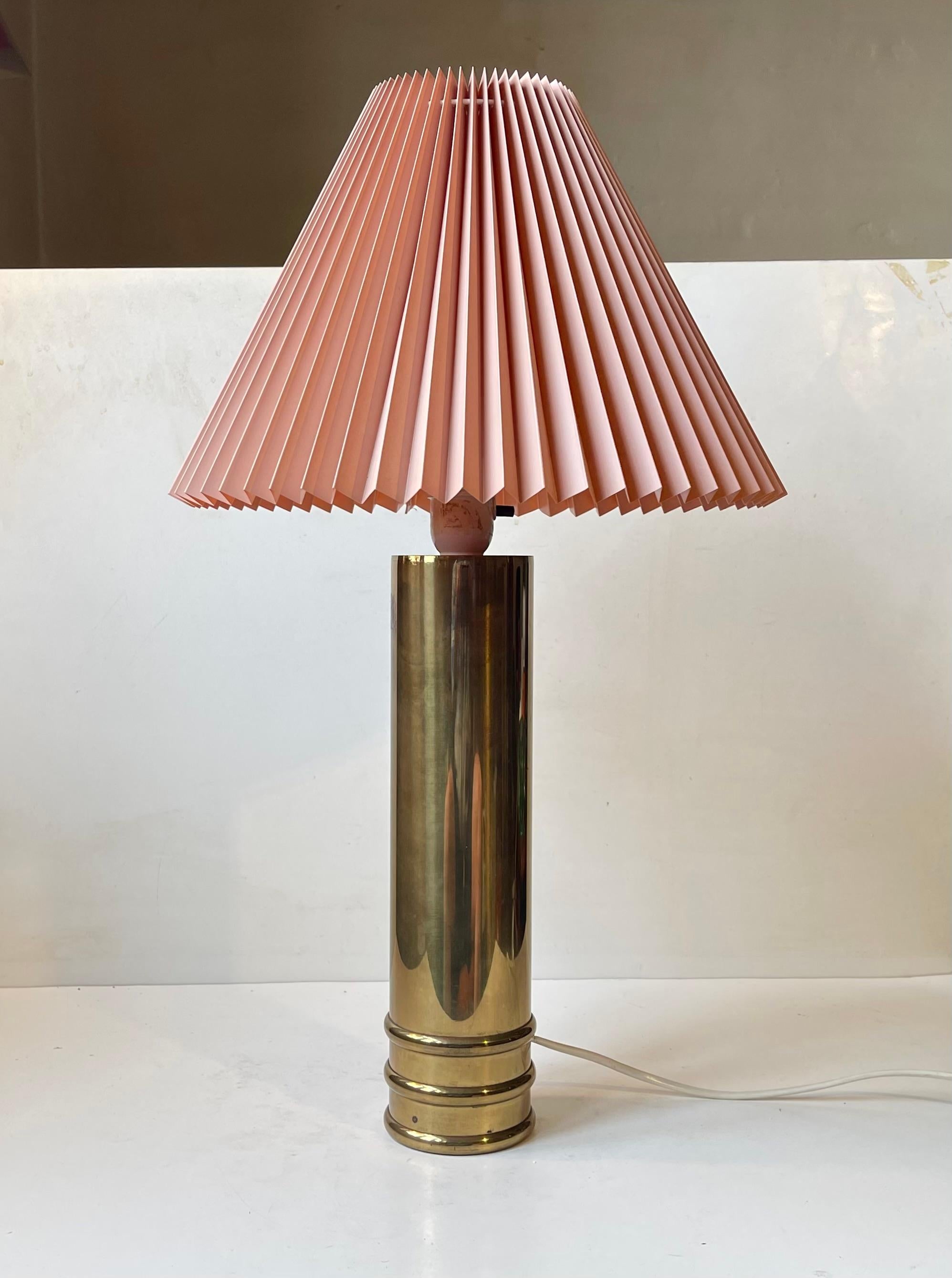 Elegant cylindrical table lamp executed in solid brass and featuring a fluted face-powder-pink lamp shade in paper/textile. Designed and manufactured by Bergboms in Sweden circa 1960-68. The version model B09 are more commonly seen in white marble.