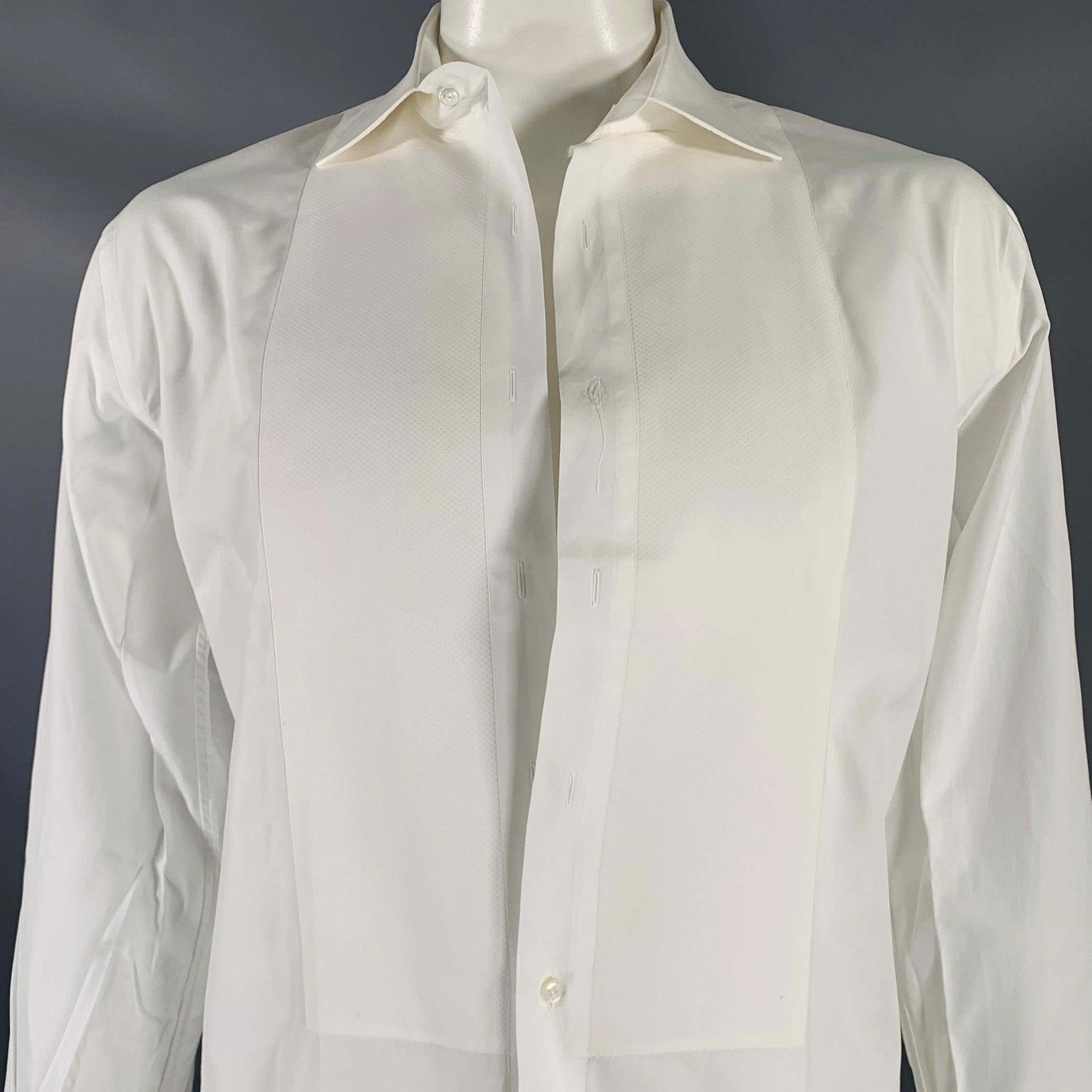 BERGDORF GOODMAN long sleeve tuxedo shirt
in a white cotton woven fabric featuring a tailored fit, tuxedo bib front, French cuffs, and button closure. Tuxedo studs and cufflinks not included. Made in Italy.Very Good Pre-Owned Condition. Minor signs