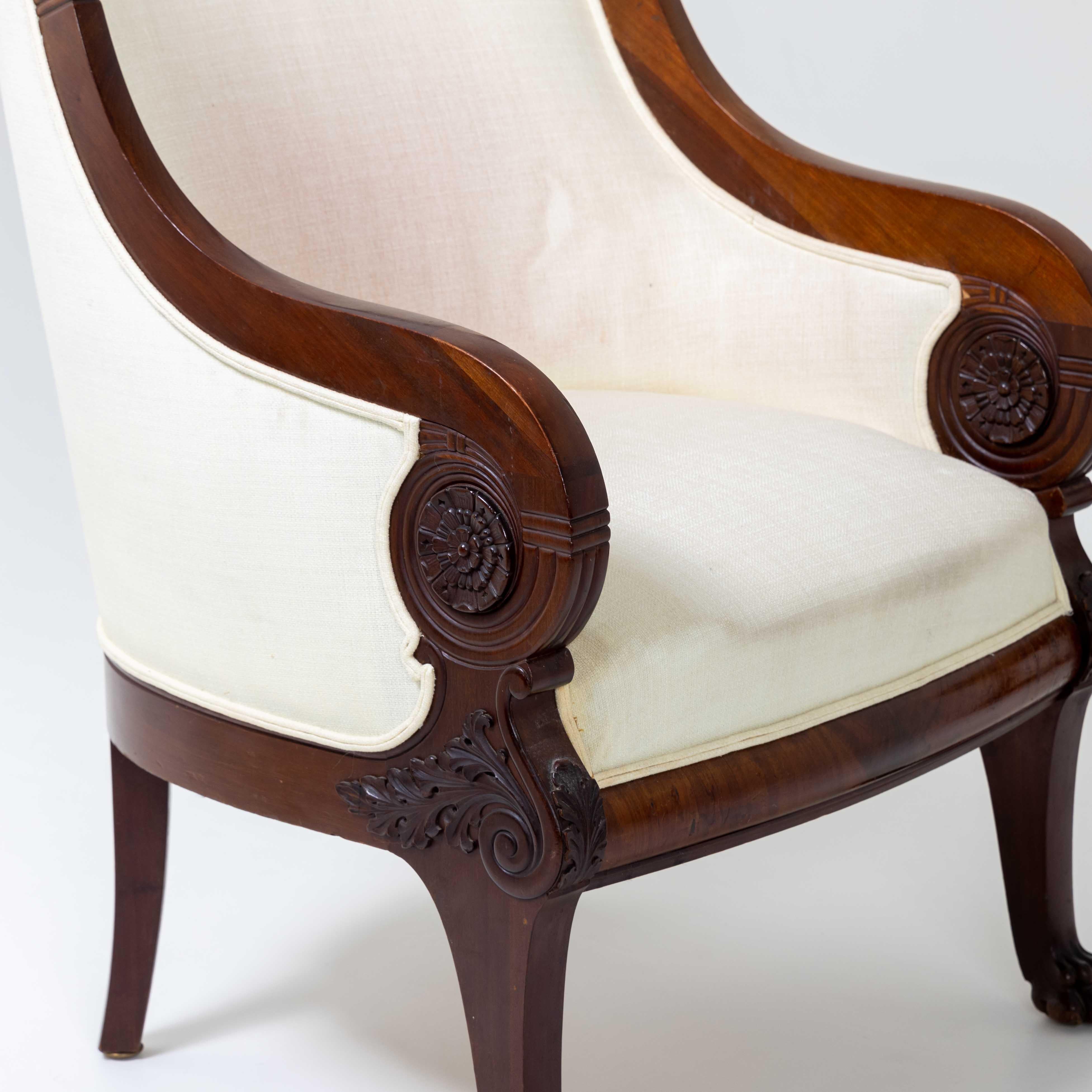 Bergère on lion paws with carved leaf decorations on the armrests and high elegantly curved backrest. The armchair was completely polished by hand and newly upholstered with a creamy white fabric.
