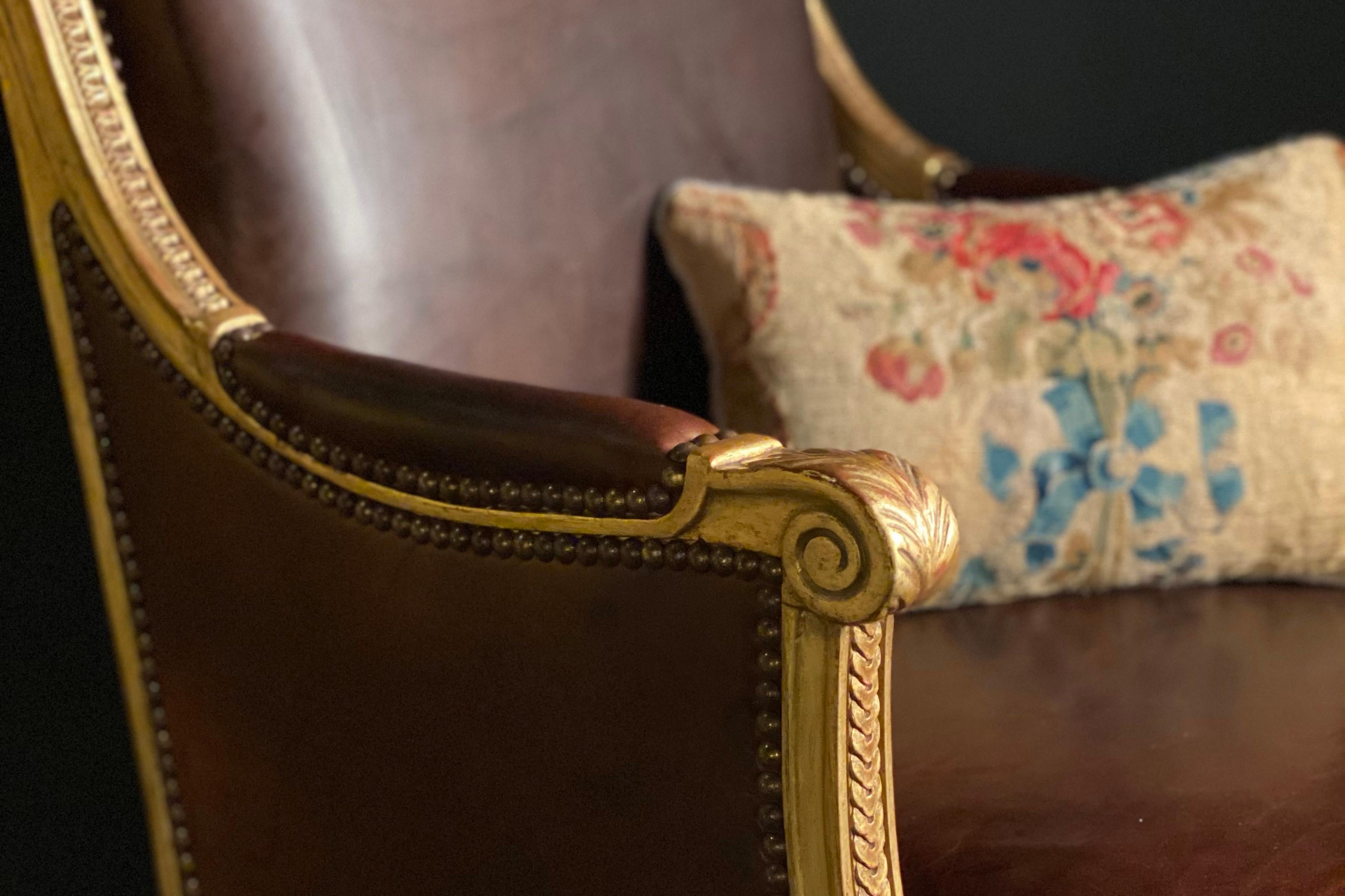 Gilded wood Louis XVI bergère with the gilding restored and the seats and backs newly upholstered in leather, a cushion was made using the original needlepoint upholstery. Stamped.