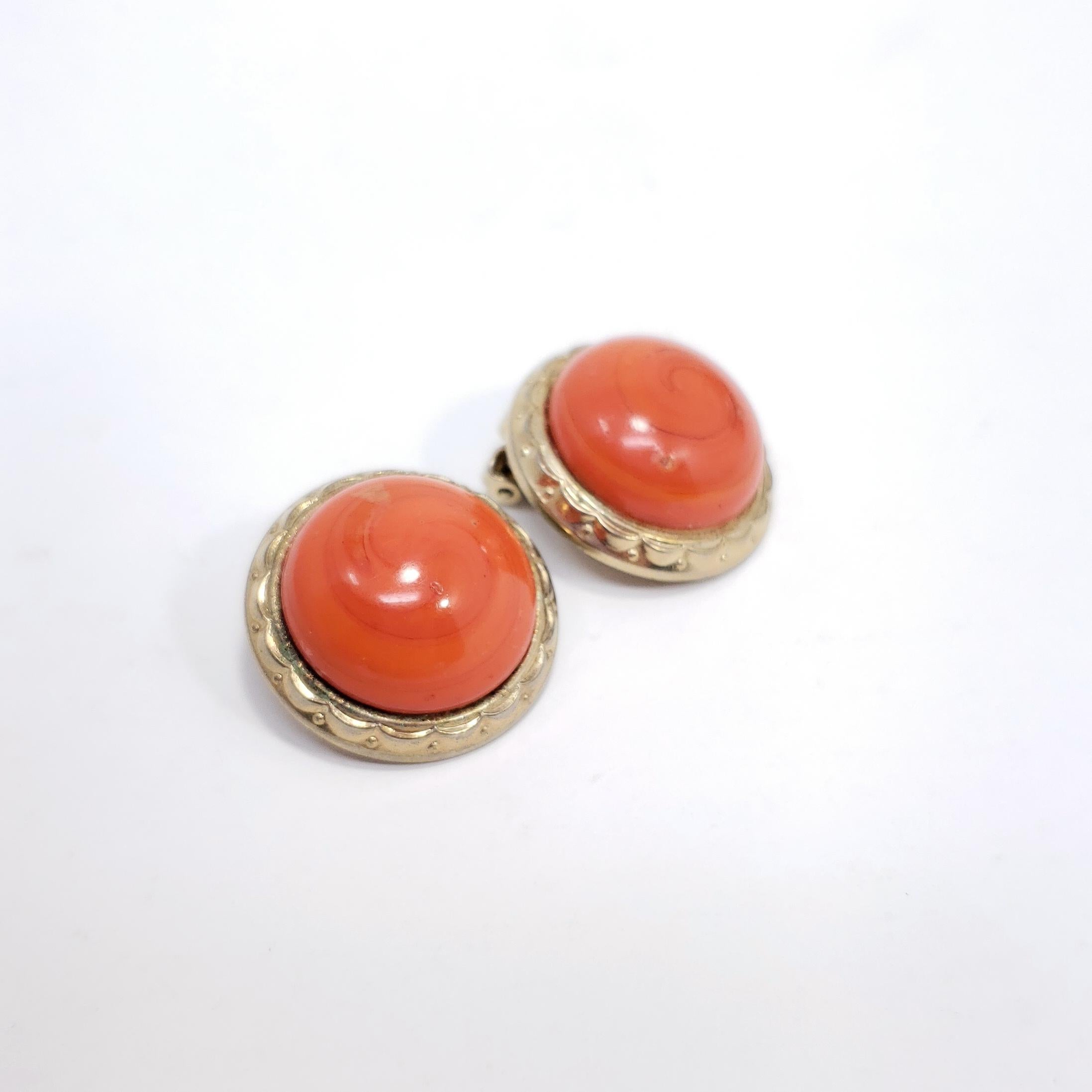 A pair of clip on earrings from costume jewelry designer Bergere. Each earring features a vibrant coral=colored cabochon set in a round golden clip.

Circa 1960s. gold plated.

Marks / hallmarks / etc: Bergere