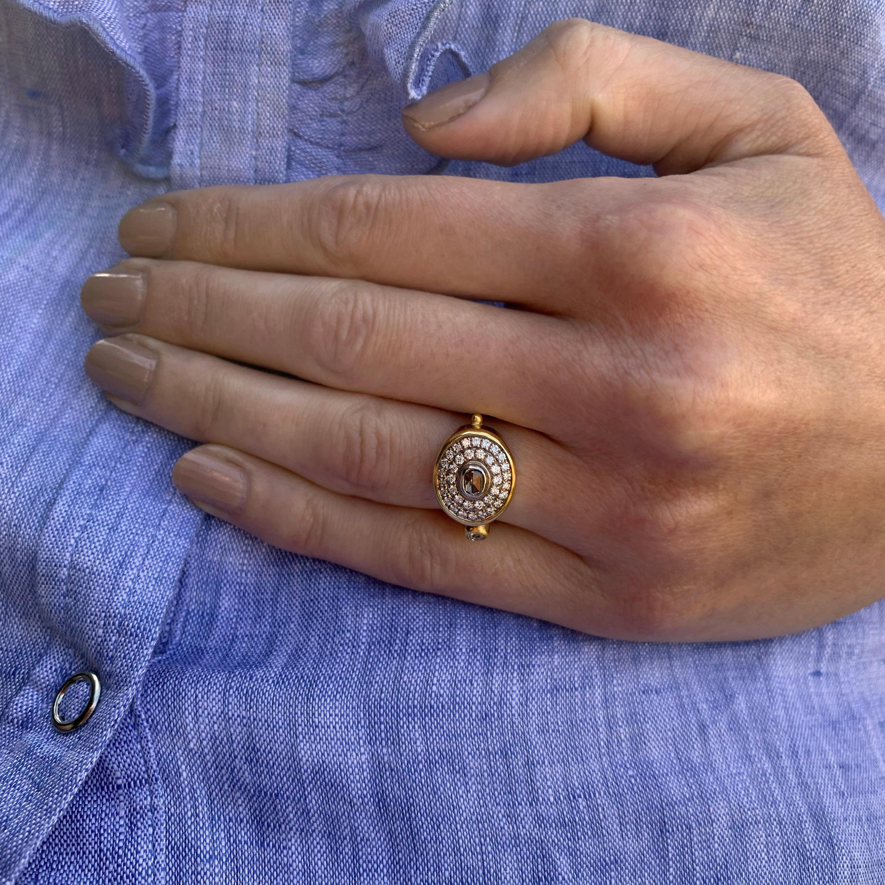 Simply stunning double halo ring pave set with rose-cut diamonds in 18k yellow gold presented on a fine gold ring: quirky, organic, elegant.
This stunning organic double-halo ring centres around an unusual oval rose-cut champagne diamond. The