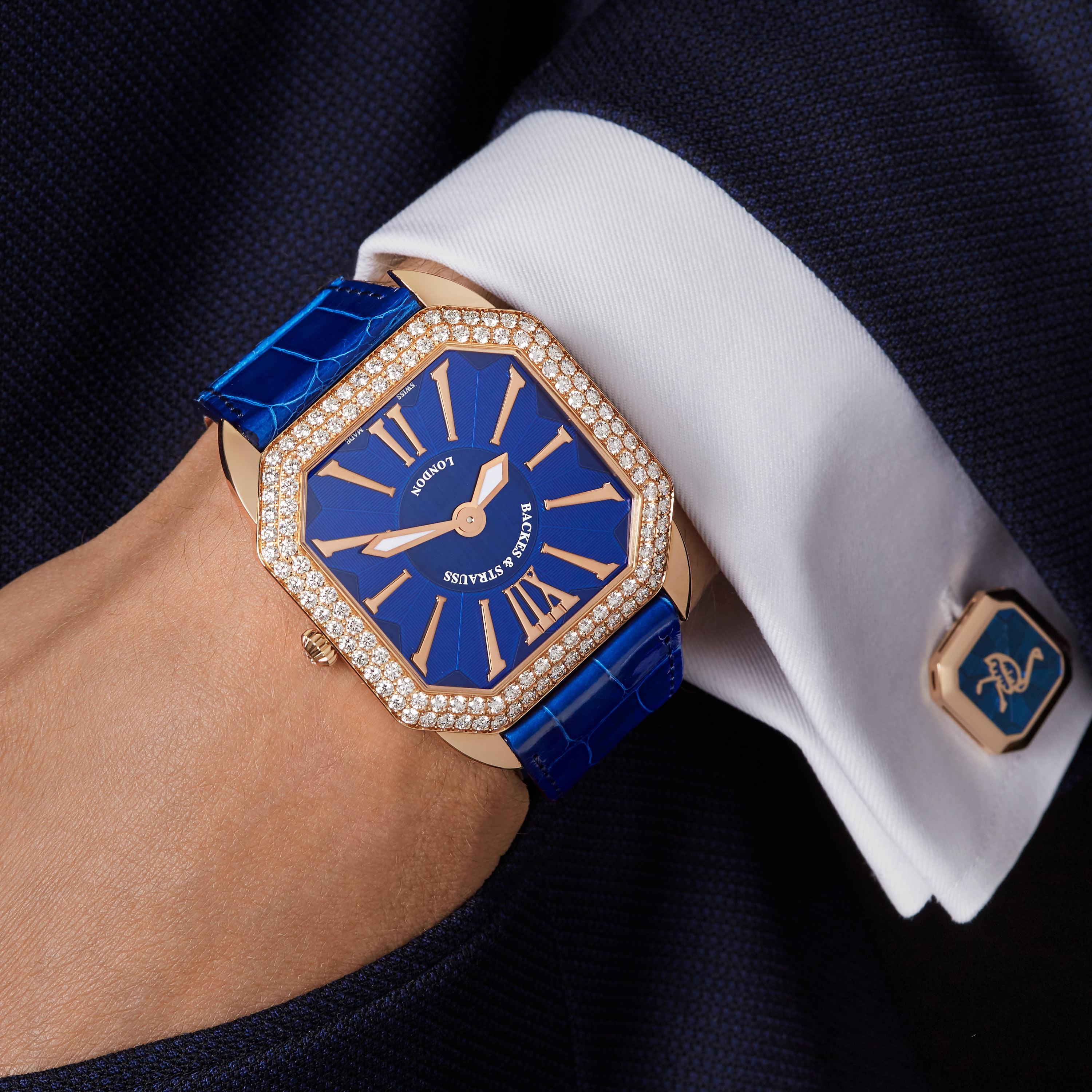 Berkeley Renaissance 43 is a luxury diamond watch for men crafted in 18kt Rose gold, featuring a blue square dial with rose gold roman numerals, mechanical movement. The crown, buckle and case are set with white Ideal Cut diamond. It is a 43 mm