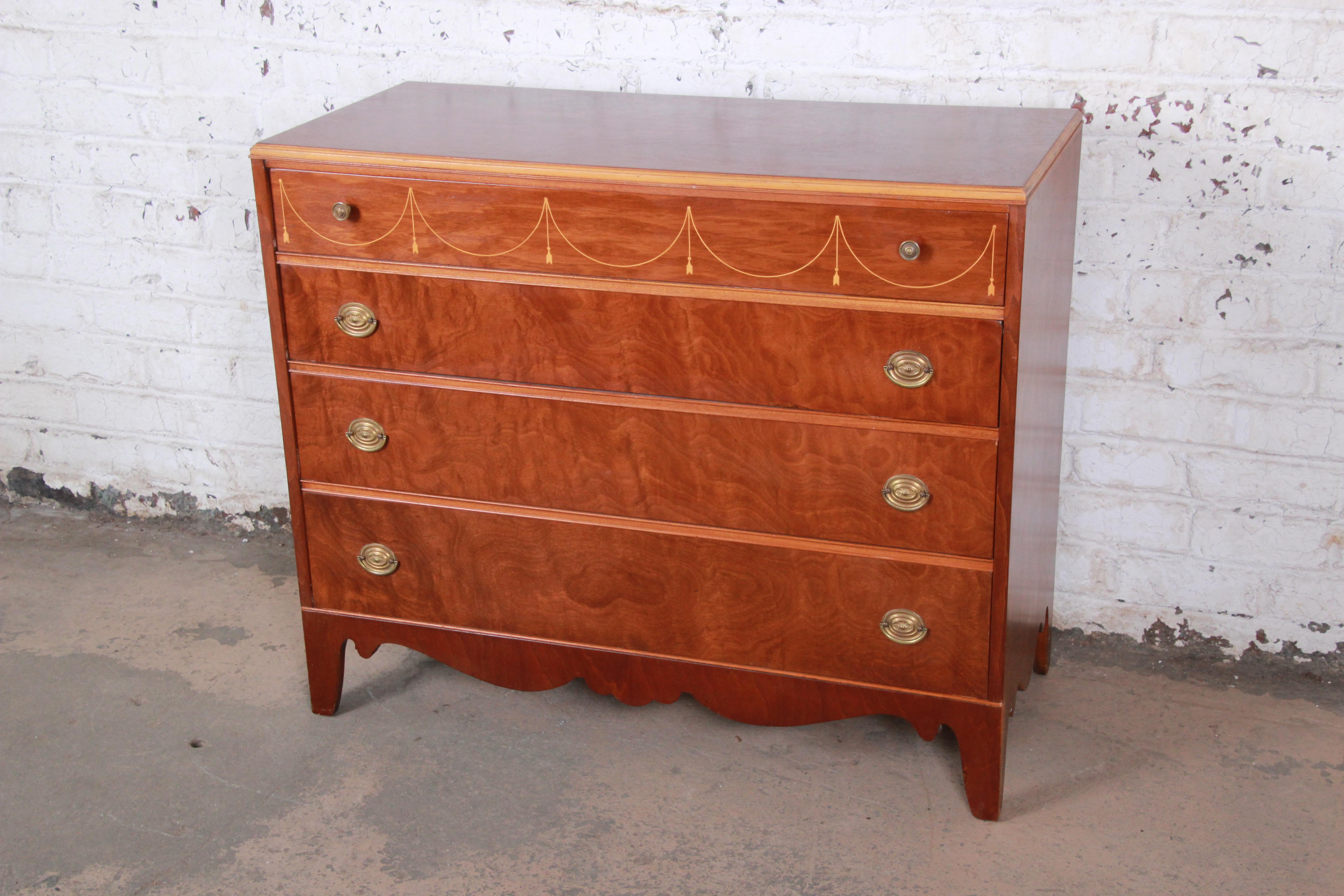 A gorgeous antique mahogany French style dresser by Berkey & Gay, circa 1930s. The dresser features beautiful mahogany wood grain and nice inlaid details. It offers ample storage, with four deep dovetailed drawers. Brass hardware is original, and