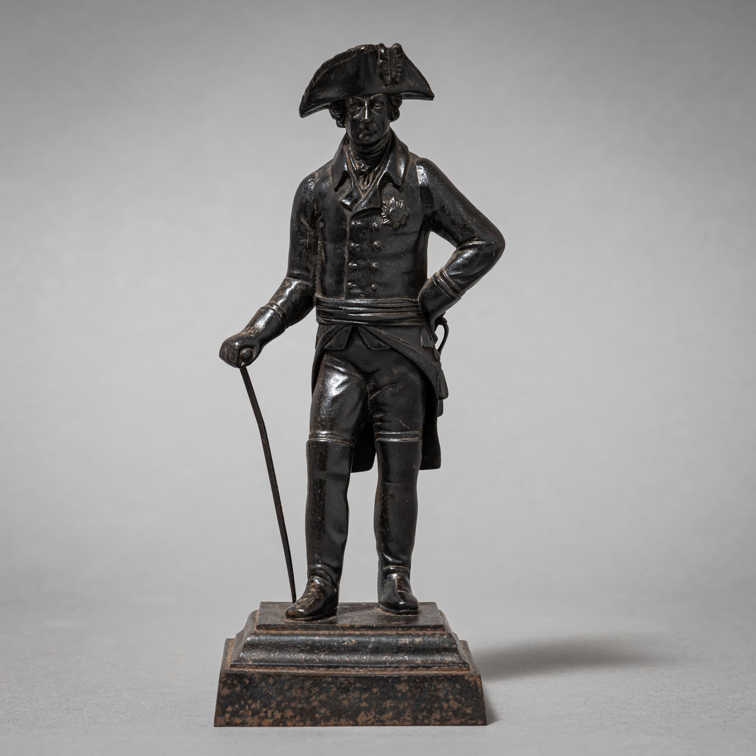 Fein gearbeitete Berliner Eisenstatuette, die Friedrich den Großen (Friedrich II. von Preußen, 1712-1786) in Uniform mit Dreispitz, Spazierstock und Degen darstellt. Die Figur steht auf einem gestuften Sockel und weist die charakteristische dunkle