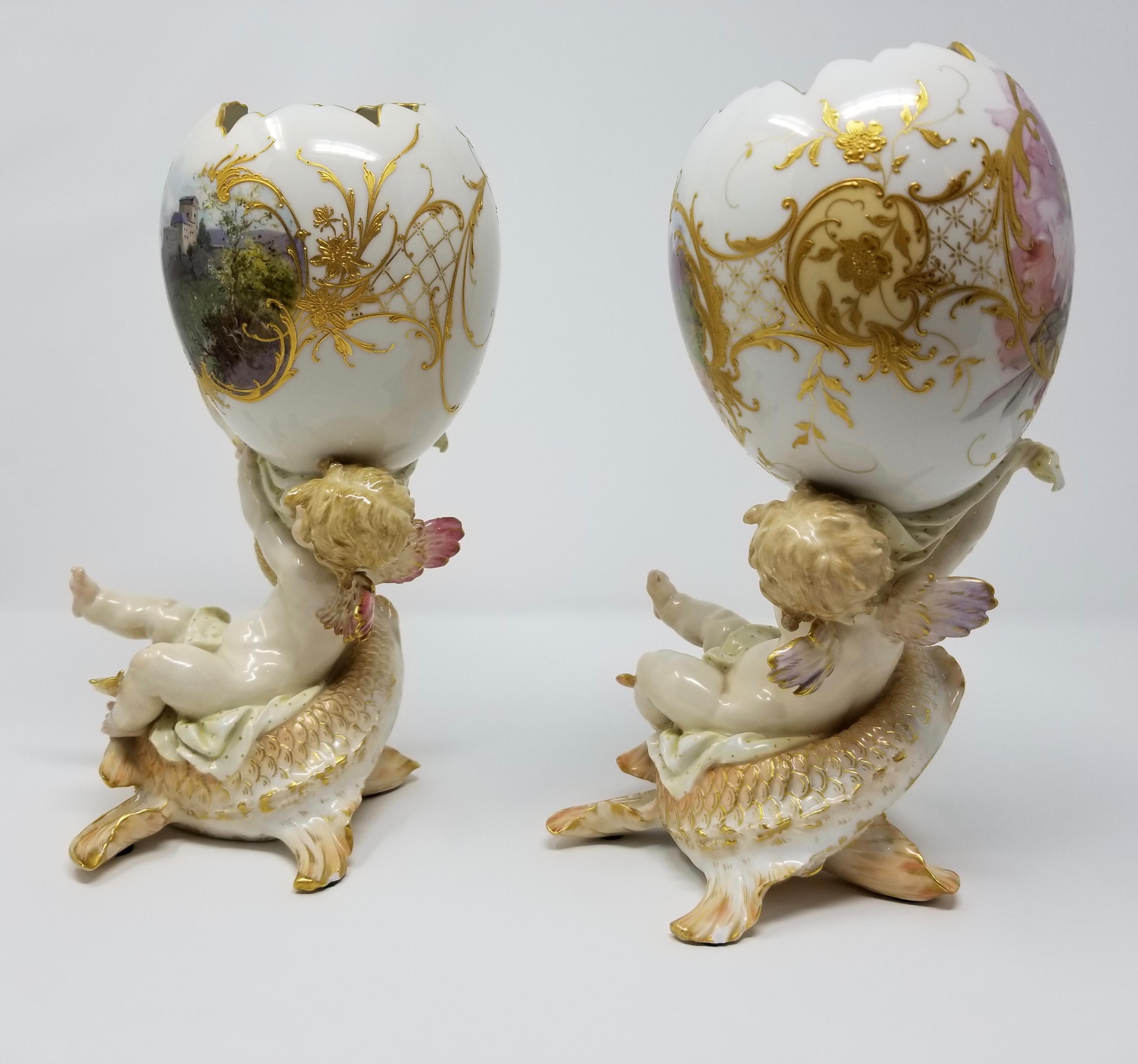 A fine pair of antique Berlin KPM figural porcelain egg shaped vases with cupids riding dolphins and Weichmalerei decor. Each pair is beautifully hand painted with bouquets of flowers, landscape and castle designs, and further elaborated with hand