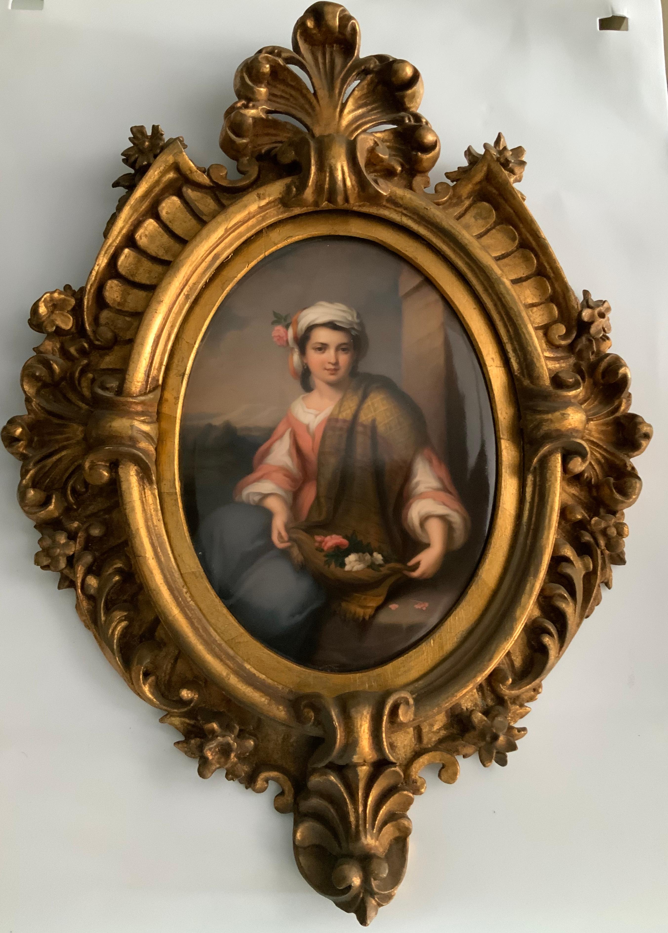 A porcelain plaque portrait from KPM that depicts a young girl sitting in a stone bench after gathering some roses in her shawl and embellish her turban with one of them. Beautifully carved gilt frame that features Prince of Wales feathers, acanthus