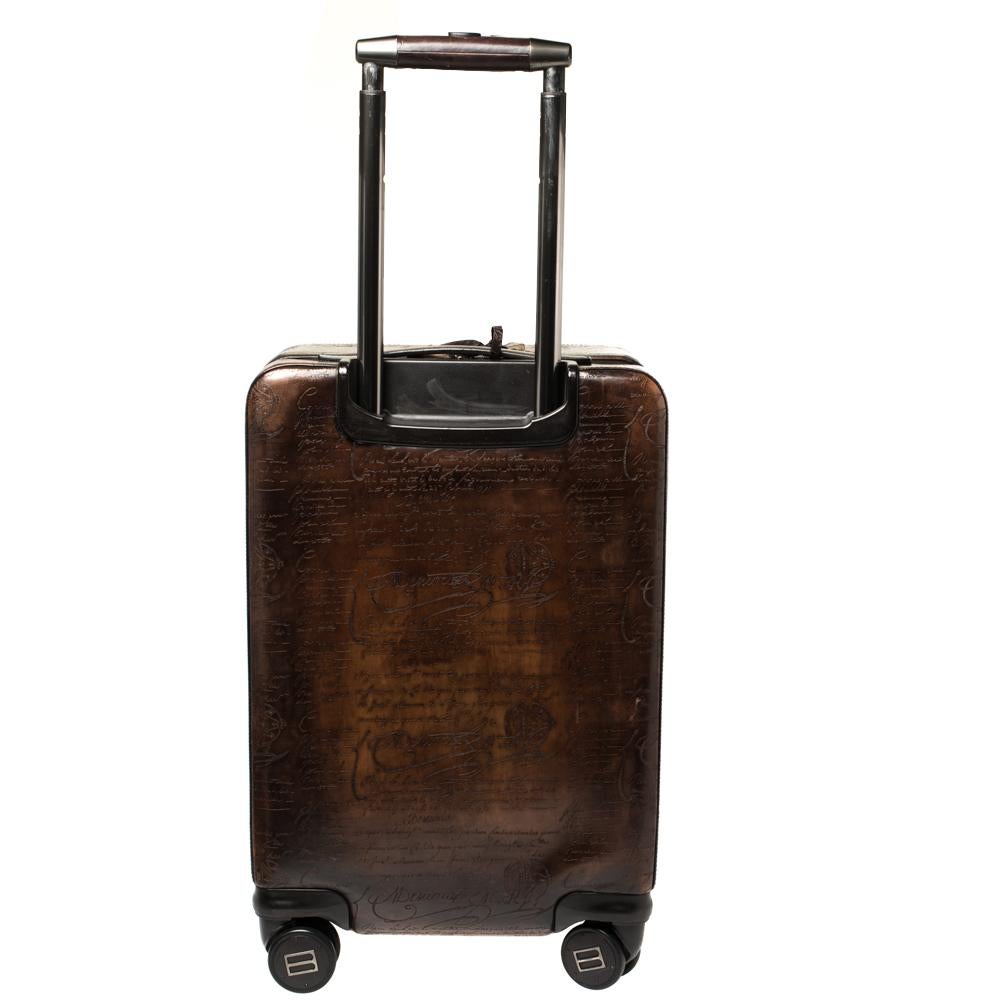This rolling suitcase by Berluti is an apt travel accessory with an elegant silhouette. It is made from Scritto leather, trims, tag, and a front zip closure. It features silver-tone hardware and comes with four roller wheels and an expandable handle