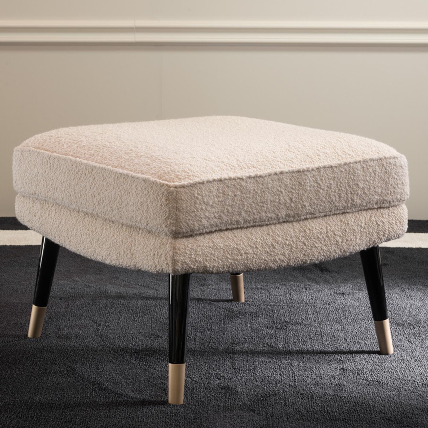 A comfortable seat with a Classic allure, this refined pouf can be arranged in multiples or paired with the Bernadette sofa to create a lounge look in a modern living room or bedroom. The midcentury inspiration is revealed in the conical wooden legs