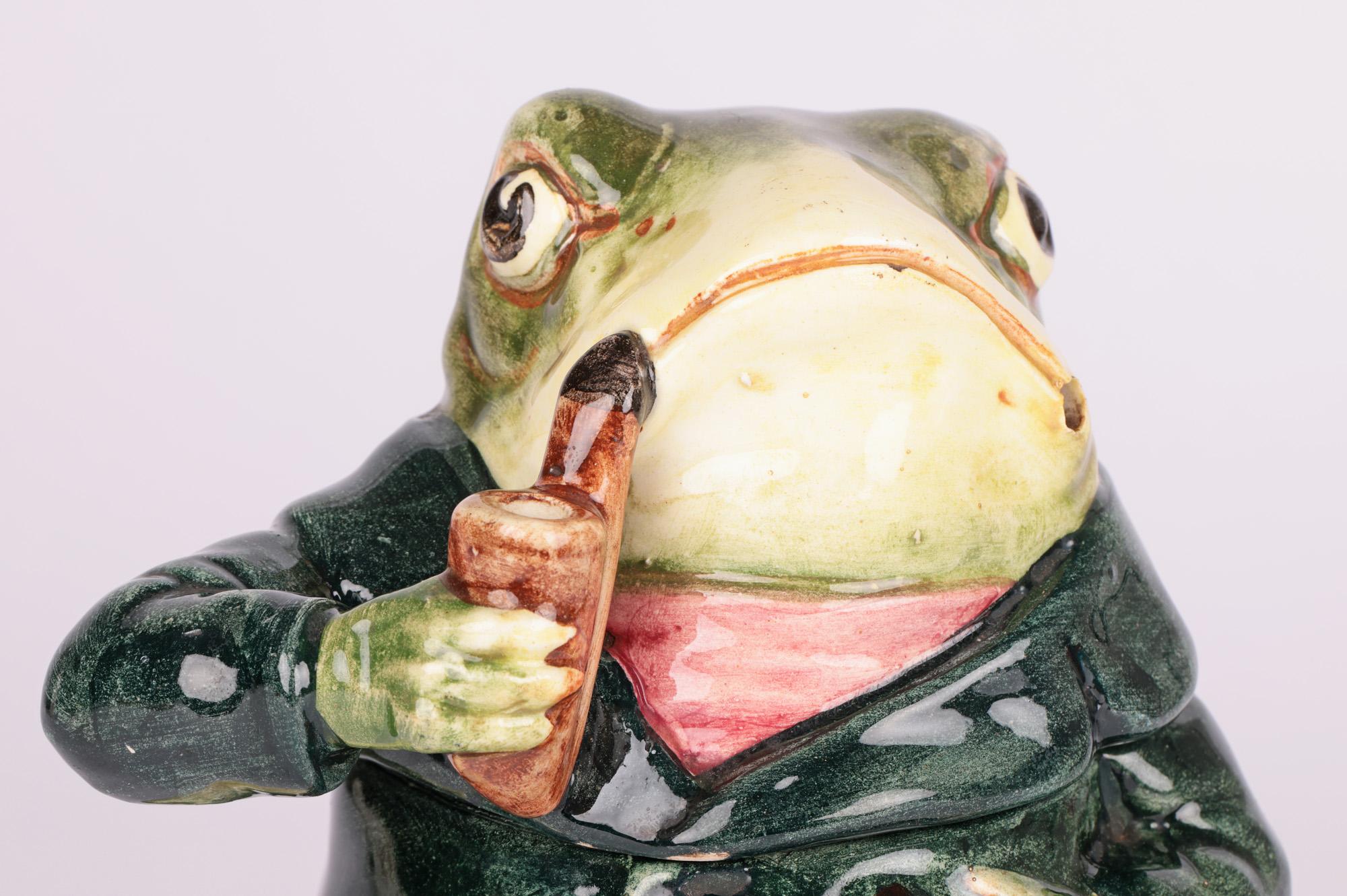 A scarce novelty Austrian majolica pottery tobacco jar modelled as a frog attributed to Bernard Bloch and dating from the latter 19th century. The lightly potted jar portrays a frog wearing a buttoned green jacket and pink cravat. He rests on leg on