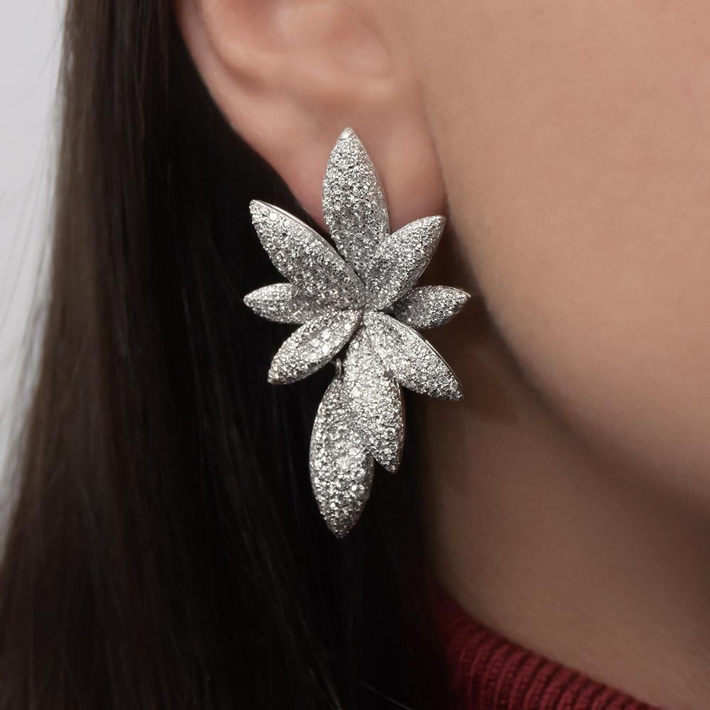 Crafted by Bernard Grosz in 18KT white gold these magnificent flower earclips are set with 840 round brilliant diamonds totaling 6.81 carats.  The flowers are composed of eight petals and the ninth petal is a drop that is detachable. The petals are