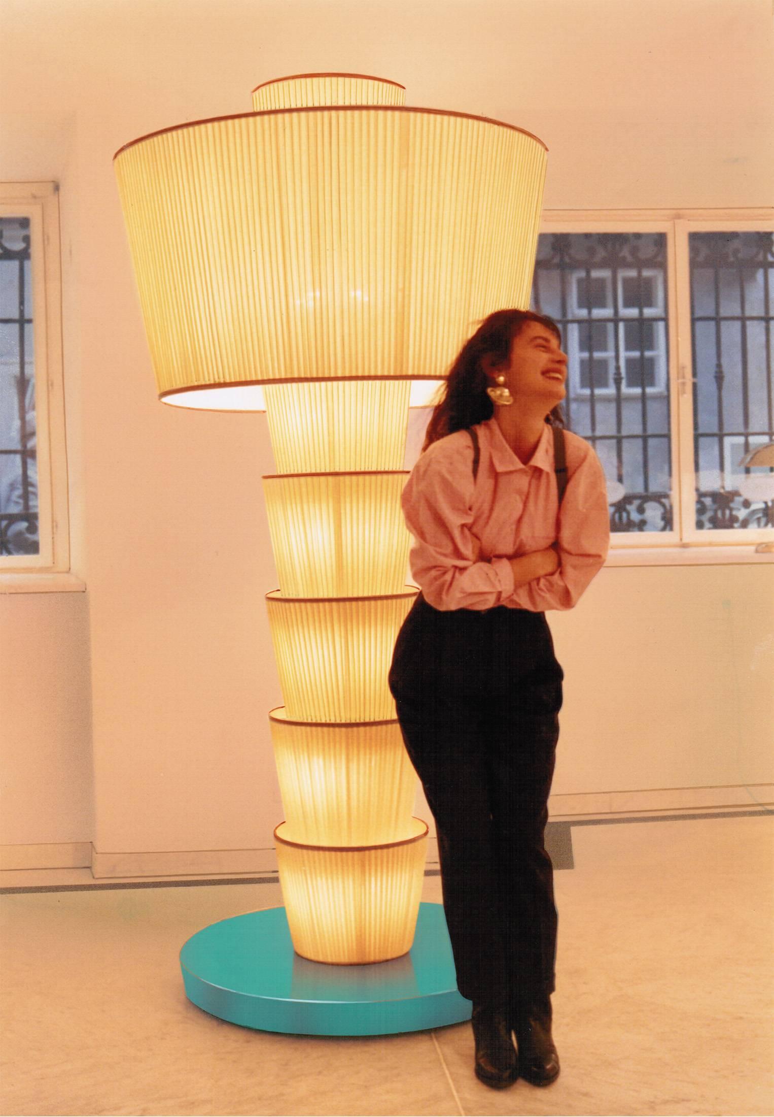 También disponible en versión de cristal.

Una lámpara de pie de tamaño monumental, diseñada por el coreógrafo Bernd Roger Bienert en 1989 para Woka Lamps. 
 
Todos los componentes cumplen la normativa UL; con un cargo adicional, elaboraremos una