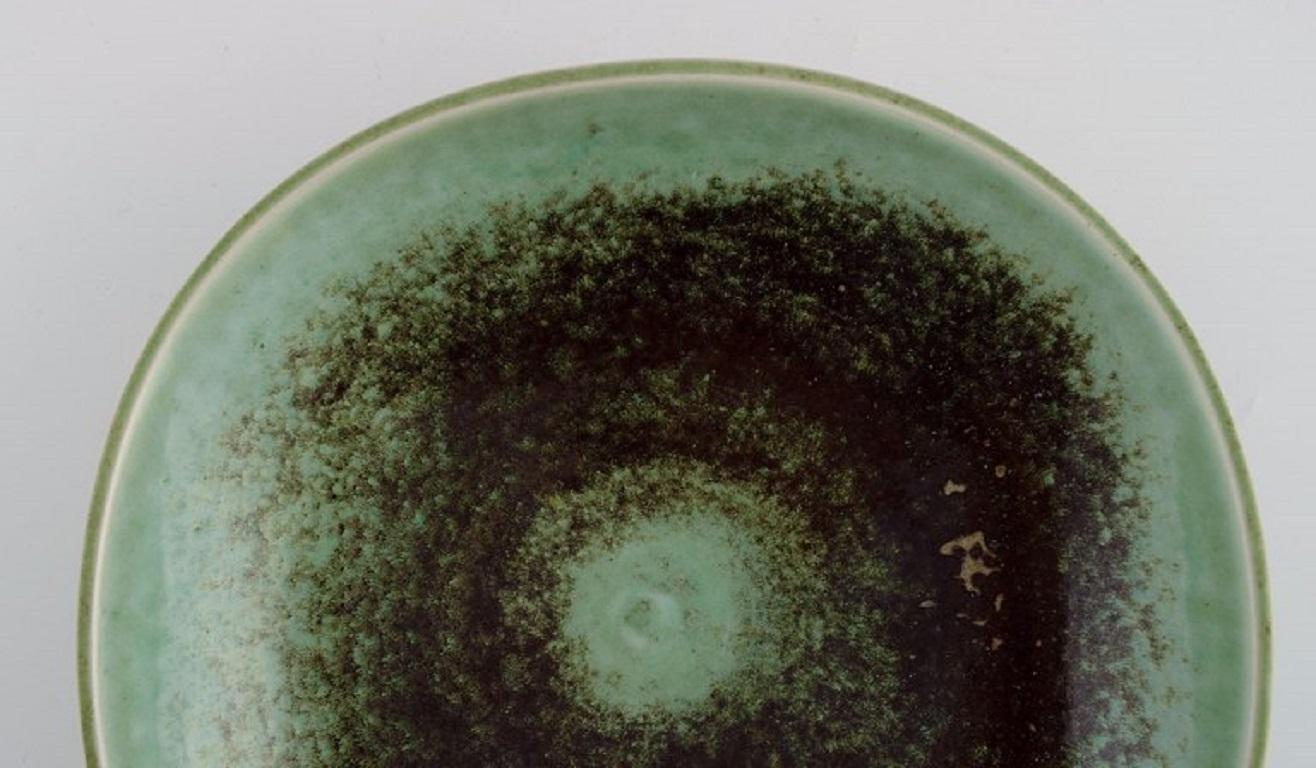 Berndt Friberg (1899-1981) for Gustavsberg Studio. 
Bowl on foot in glazed ceramics. Beautiful glaze in turquoise and dark shades. 
Dated 1966.
Measures: 21 x 5 cm.
In excellent condition.
Signed and dated.